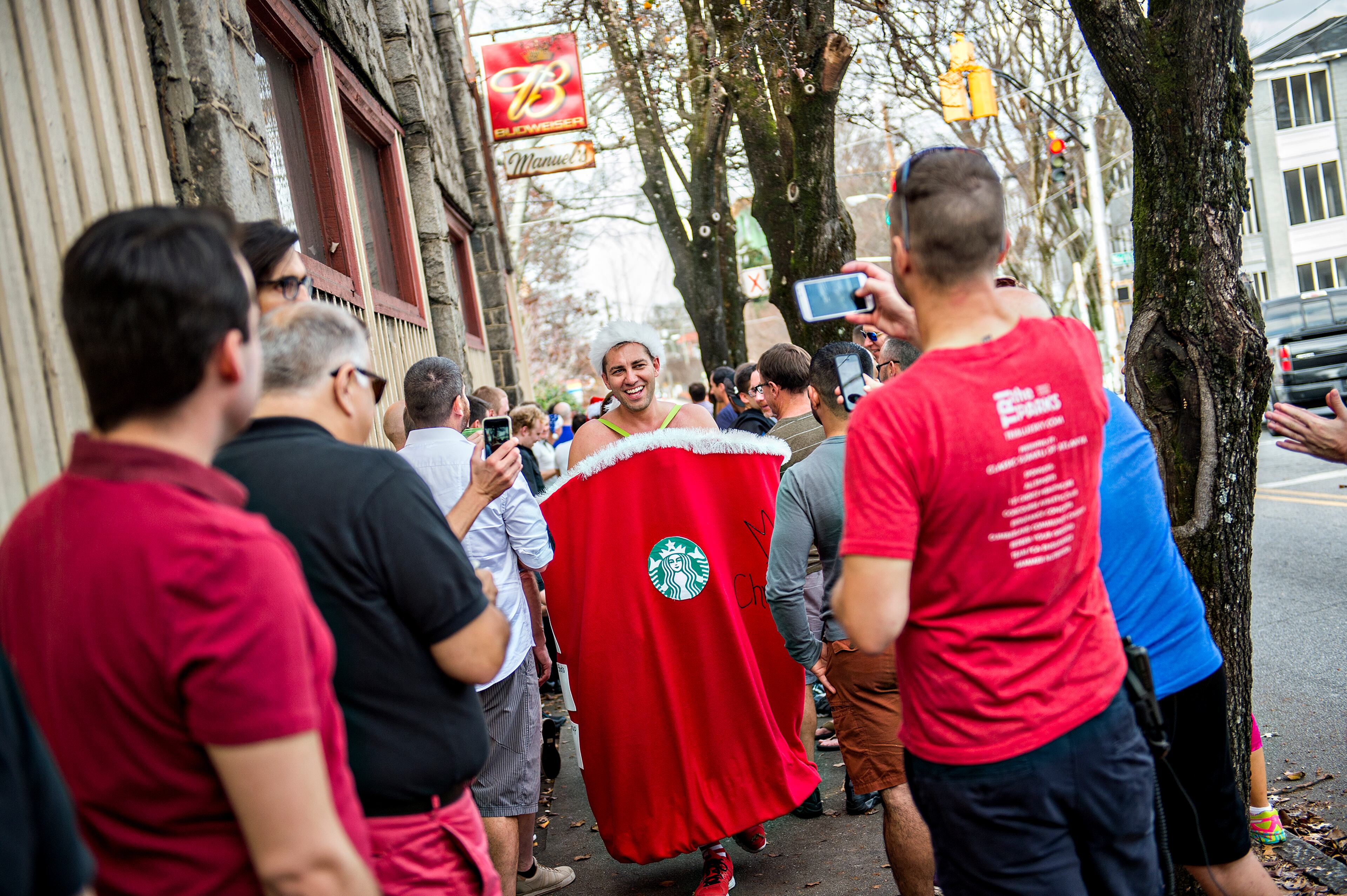 December 12, 2015 Atlanta - Erik Metzger (center) is greeted by onlookers as he returns to Manuel's Tavern in Atlanta at the end of the annual Atlanta Santa Speedo Run on Saturday, December 12, 2015. The seventh annual fun run raised over $42,000 for BlazeSports. JONATHAN PHILLIPS / SPECIAL