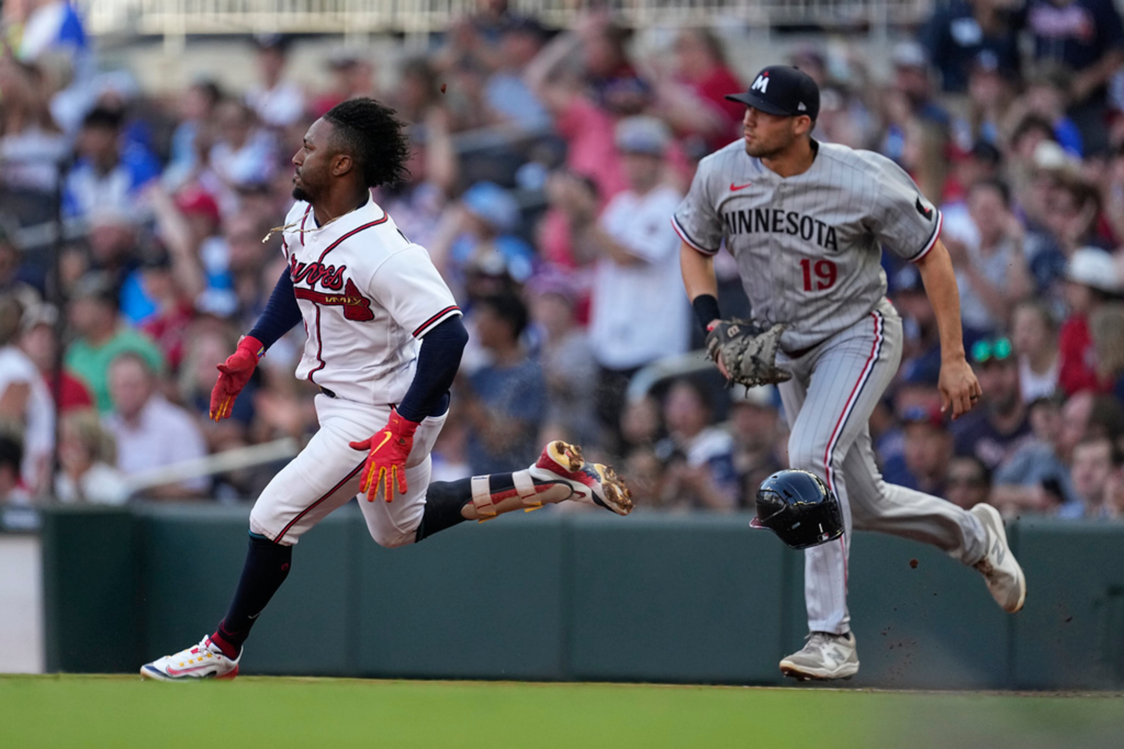 Atlanta Braves' Ozzie Albies runs past Minnesota Twins first baseman Alex Kirilloff (19) after hitting a triple during the first inning of a baseball game Tuesday, June 27, 2023, in Atlanta. (AP Photo/John Bazemore)