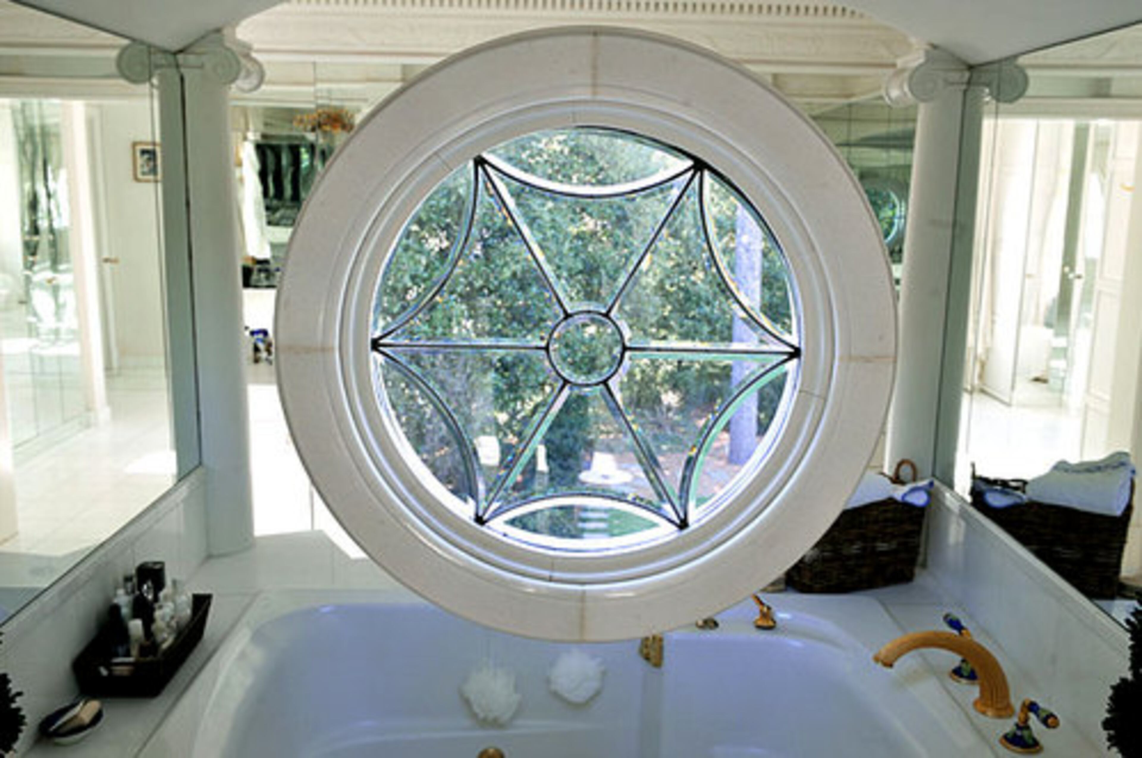 A circular glass window, which Ginny Millner uncovered in the process of turning a closet into a bathroom in the master bedroom, is surrounded by mirrors above the bathtub.