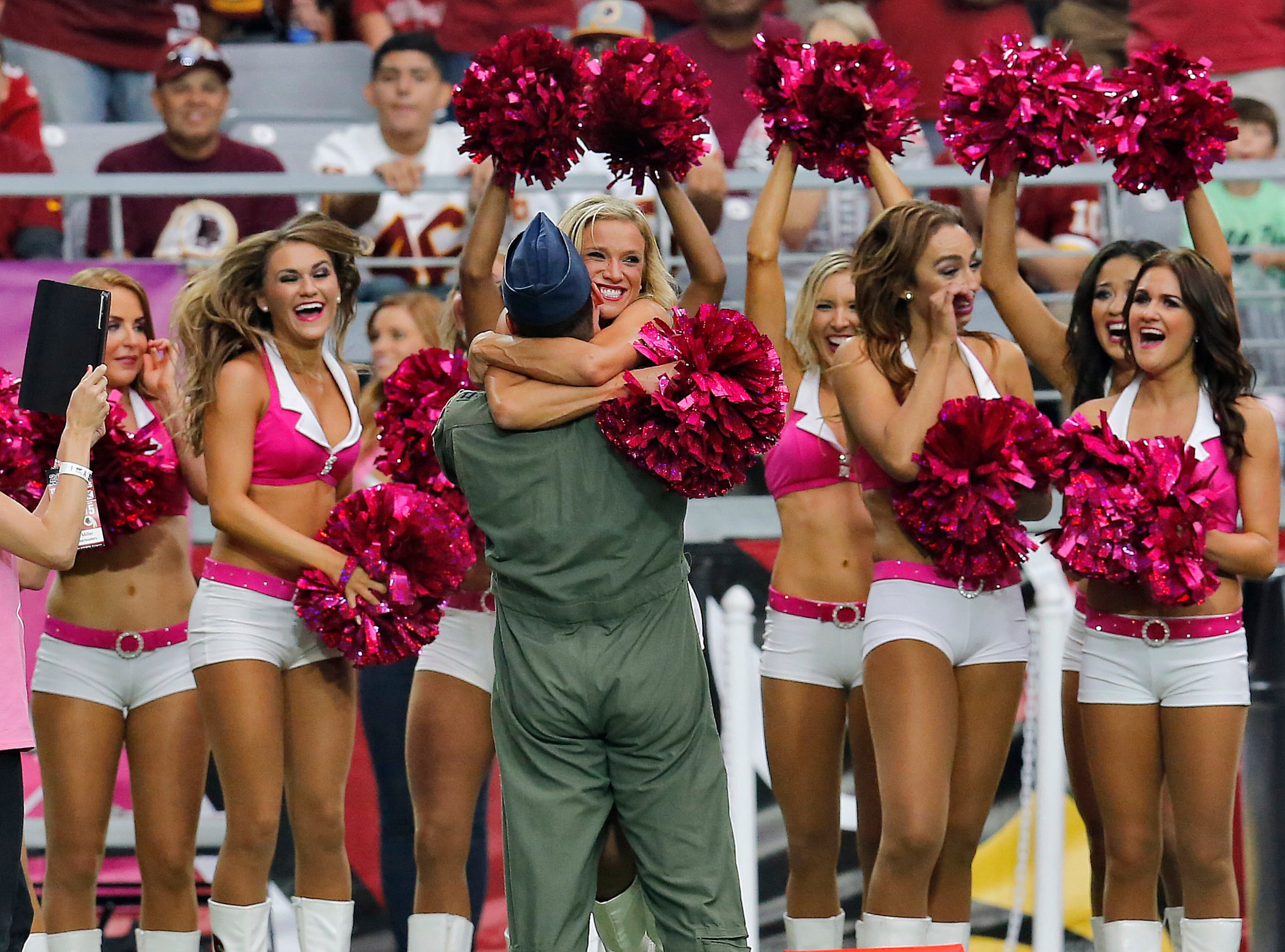 An airman hugs an Arizona Cardinals cheerleader after proposing to her during the first half of an NFL football game against the Washington Redskins, Sunday, Oct. 12, 2014, in Glendale, Ariz.(AP Photo/Rick Scuteri)