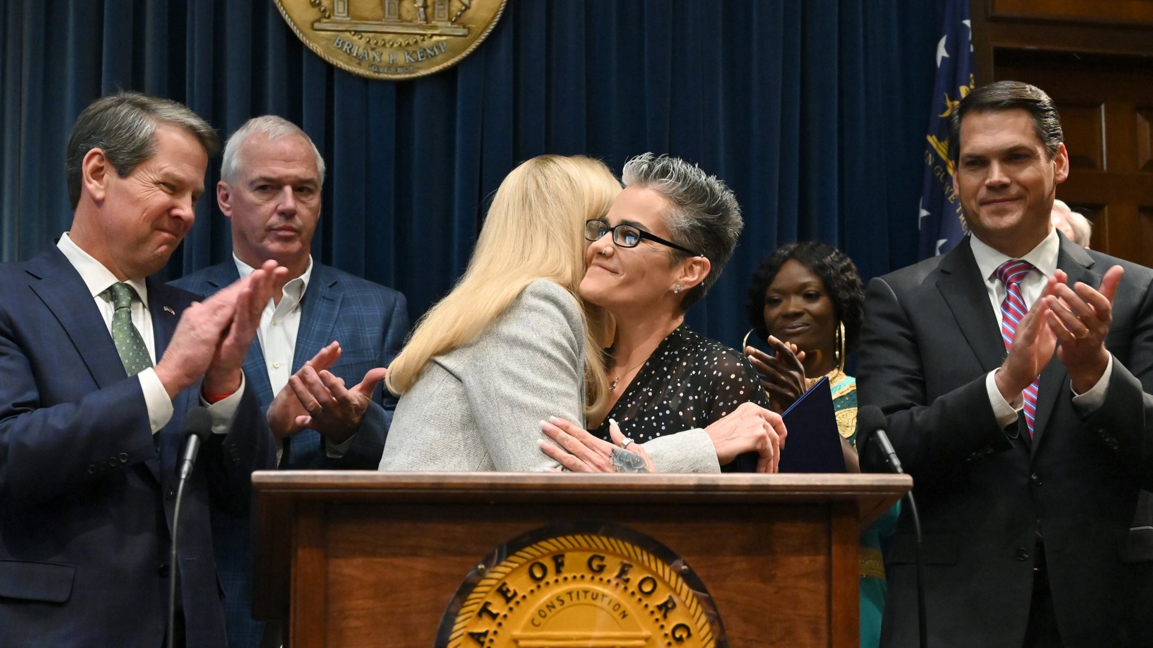 Nikki Burrell, center right, a victim of human trafficking, gets a hug from Georgia first lady Marty Kemp during a press conference Tuesday at the Capitol to announce legislative measures aimed at combating human trafficking. Gov. Brian Kemp, far left, has made the fight against human trafficking one of his top priorities for the legislative session that began last week. (Hyosub Shin / Hyosub.Shin@ajc.com)