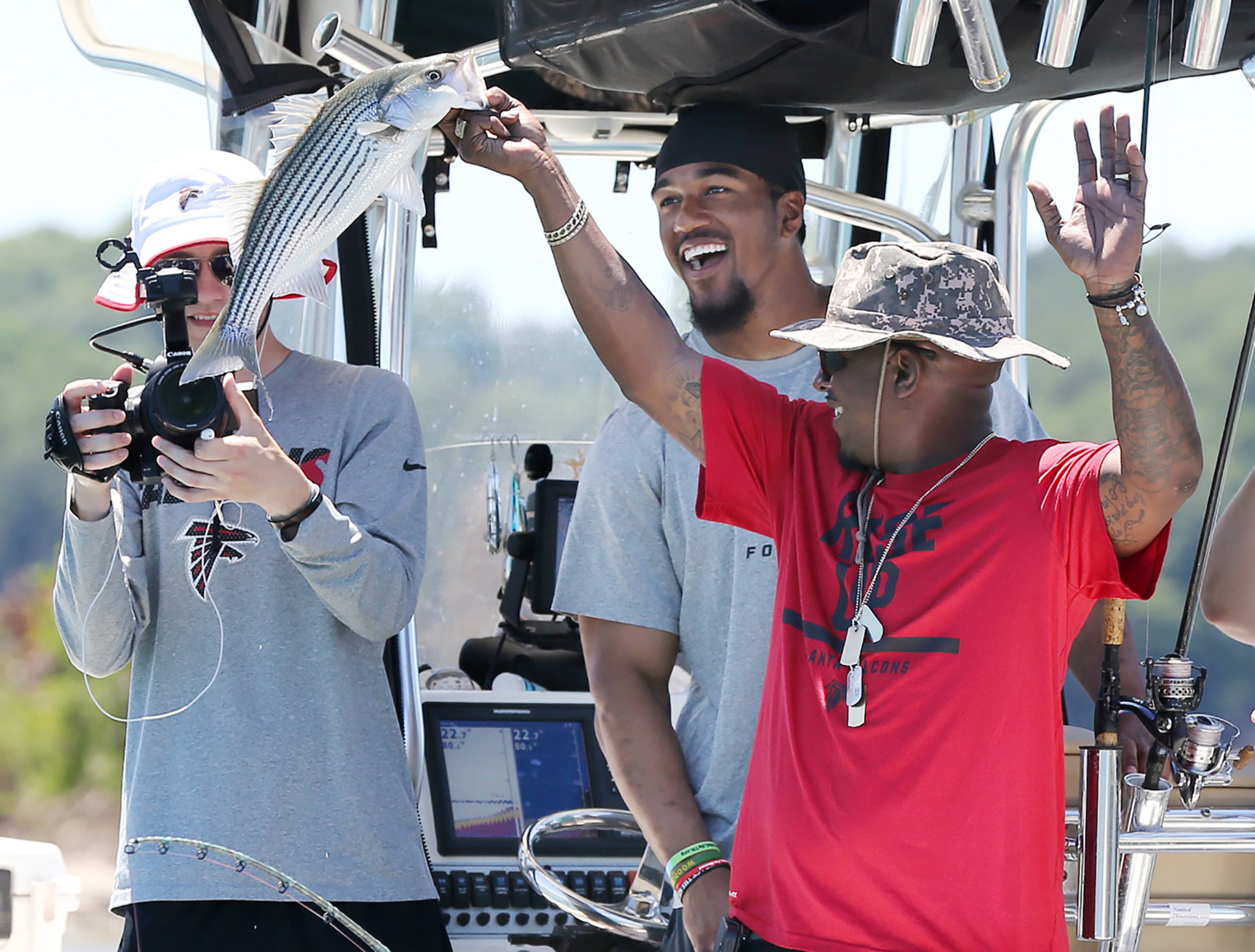 FISHING WITH THE FALCONS--060816 BUFORD: Army SGT. Lewis Walton, who served in Iraq and Afghanistan, and Falcons Vic Beasley Jr., react as Walton lands a striper fish during the 9th annual Fishing with the Falcons tournament at Lake Lanier on Wednesday, June 8, 2016, in Buford. Wounded military soldiers from Iraq and Afghanistan are paired with Falcons players, alumni, coaches and cheerleaders on individual fishing boats for an afternoon of fishing. Curtis Compton / ccompton@ajc.com