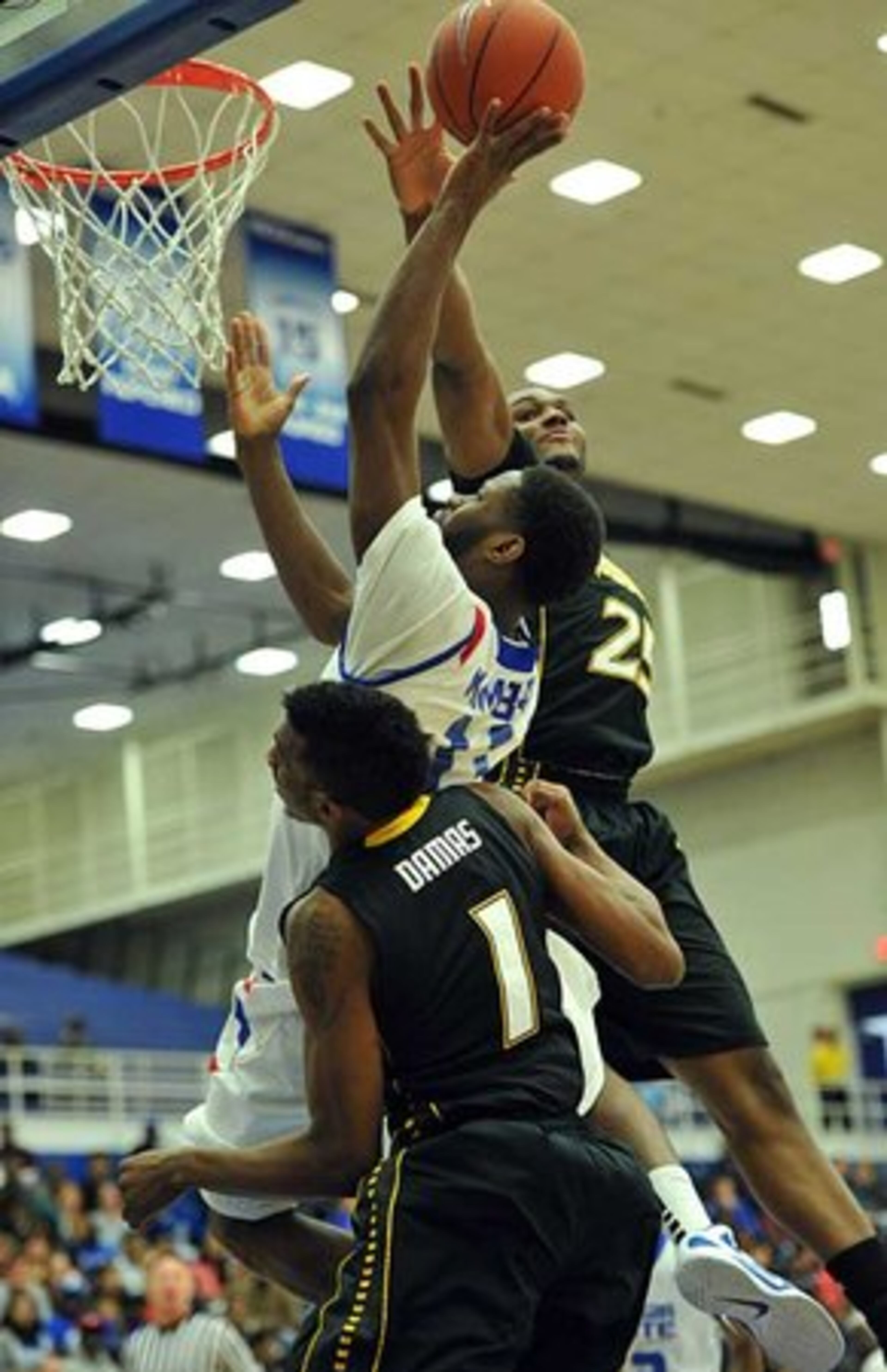 Tony Kimbro Jr. (center) is blocked by Towson forward Robert Nwankwo (background) and Towson forward Marcus Damas (1).