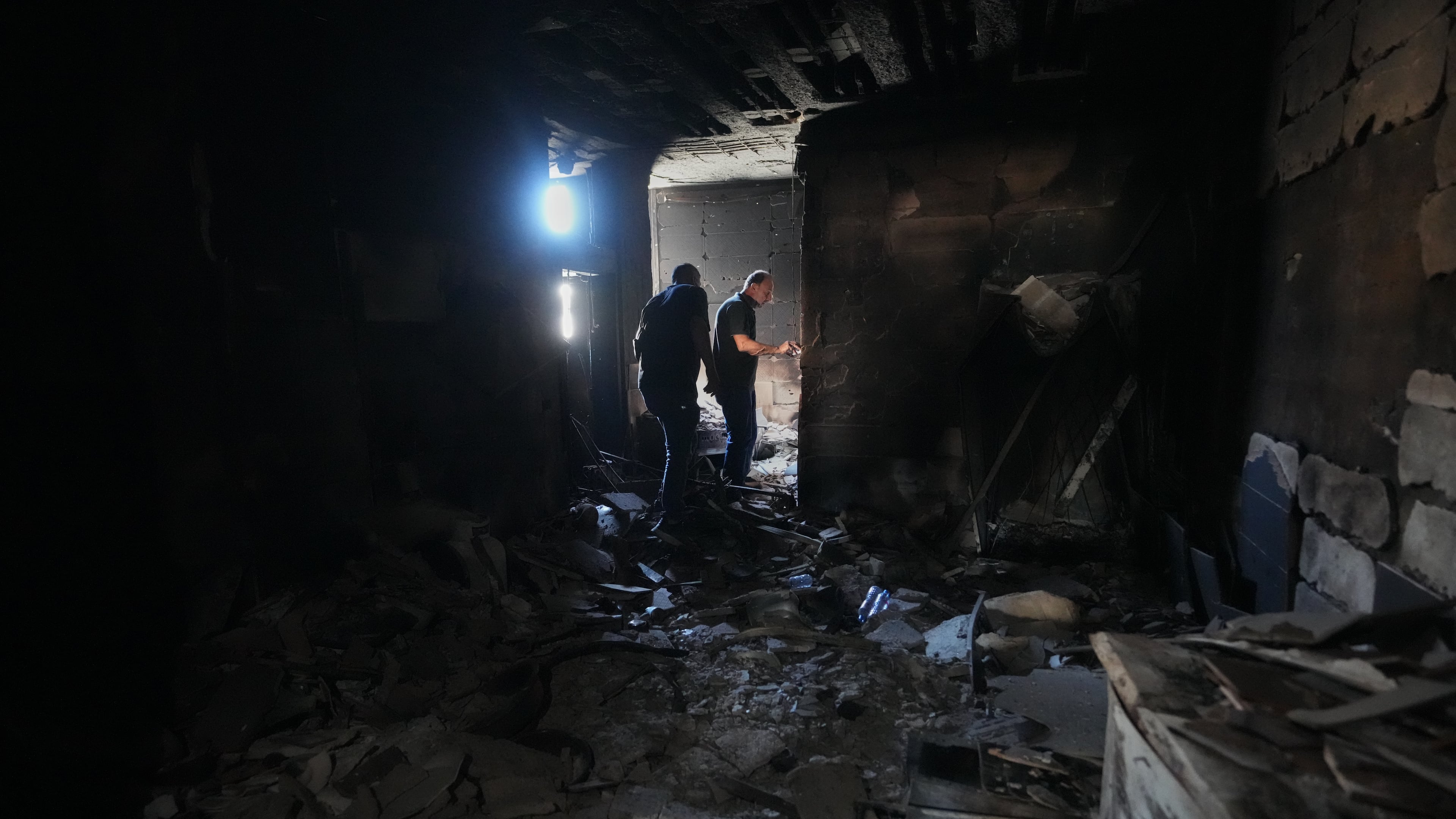 Resident Samih Haidar, right, inspects his burned apartment damaged in Israeli strikes in the southern port city of Tyre, Lebanon, Thursday, June 18, 2026. (AP Photo/Hassan Ammar)