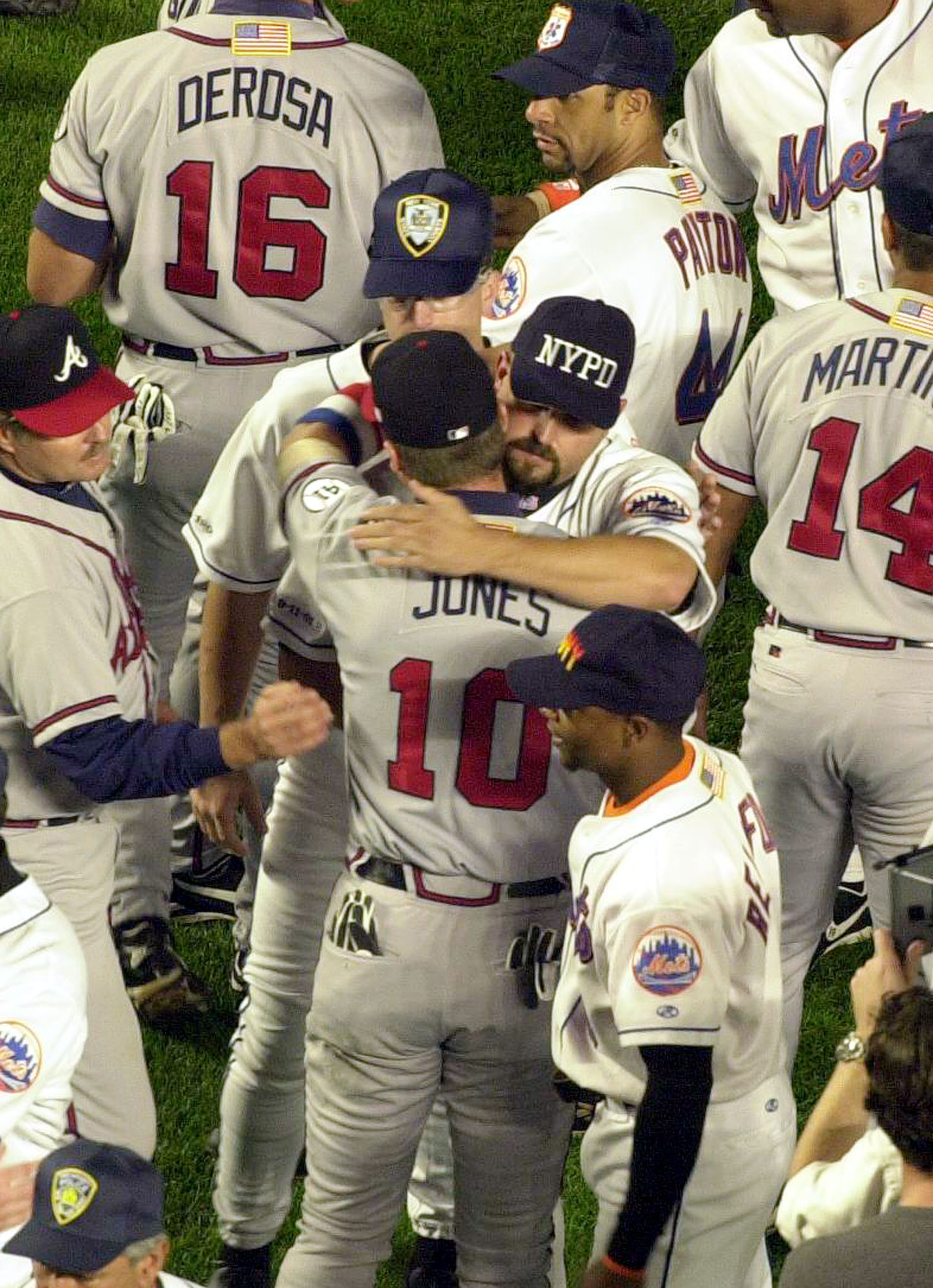 The Mets' Rick White, wearing an NYPD cap, embraces the Braves' Chipper Jones before the start of the Sept. 21, 2001, game at Shea Stadium, the first MLB game in New York after the World Trade Center attack of Sept. 11. The Mets wore caps honoring the police and fire departments for the game. (Mark Lennihan/AP)