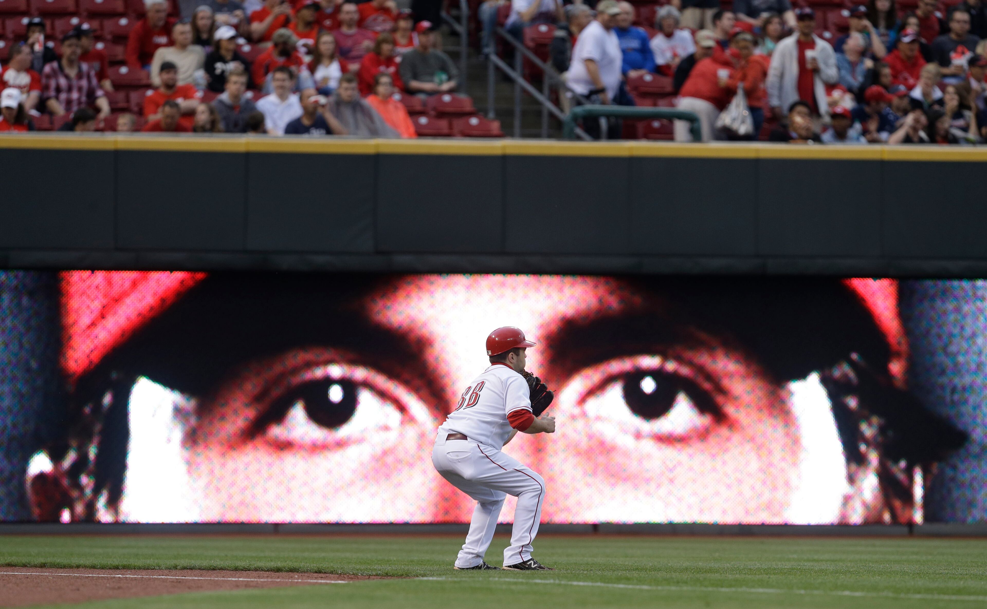 A Cincinnati Reds ball boy catches a ball in front of a display featuring the face of starting pitcher Homer Bailey.