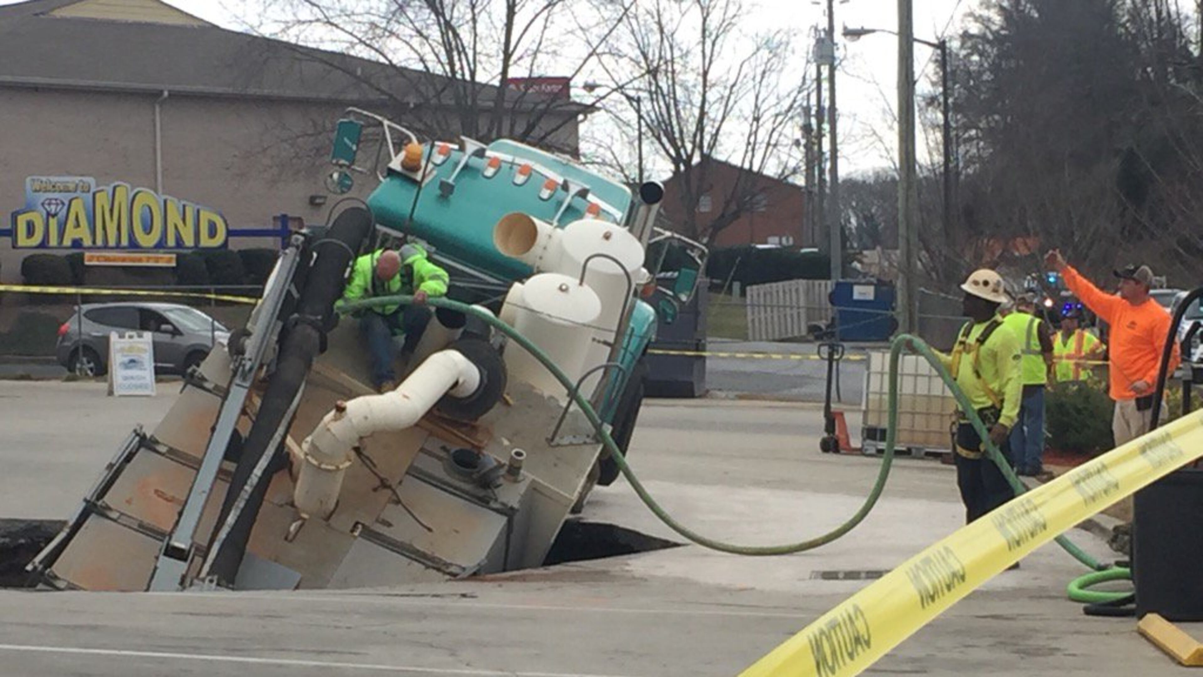 A worker climbs on a truck that is stuck in a sinkhole in Hall County. (Credit: Channel 2 Action News)