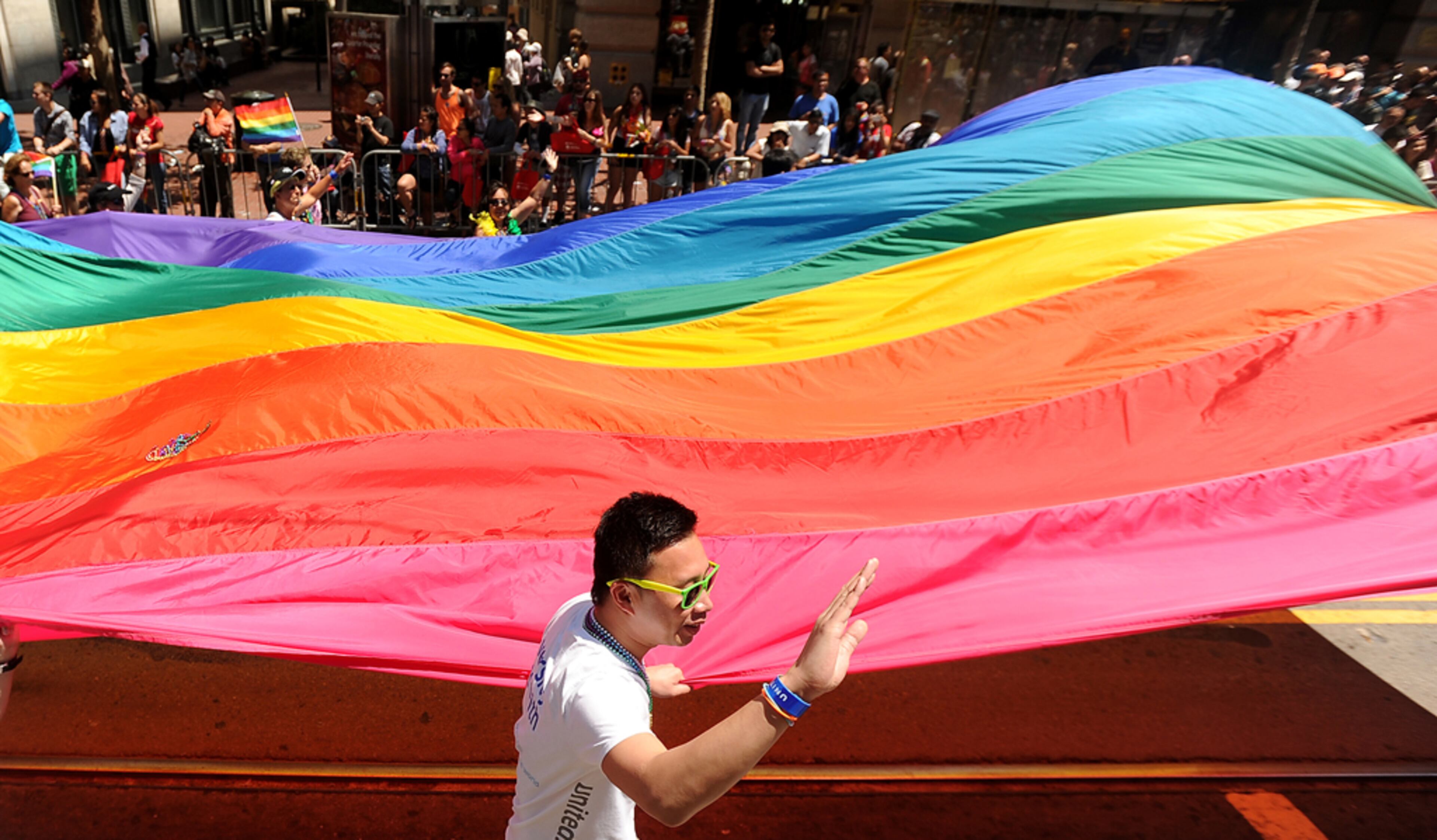 A United Airlines employee waves to spectators while carrying a rainbow flag up Market Street during San Francisco's 43rd annual Gay Pride parade on Sunday, June 30, 2013. (AP Photo/Noah Berger)