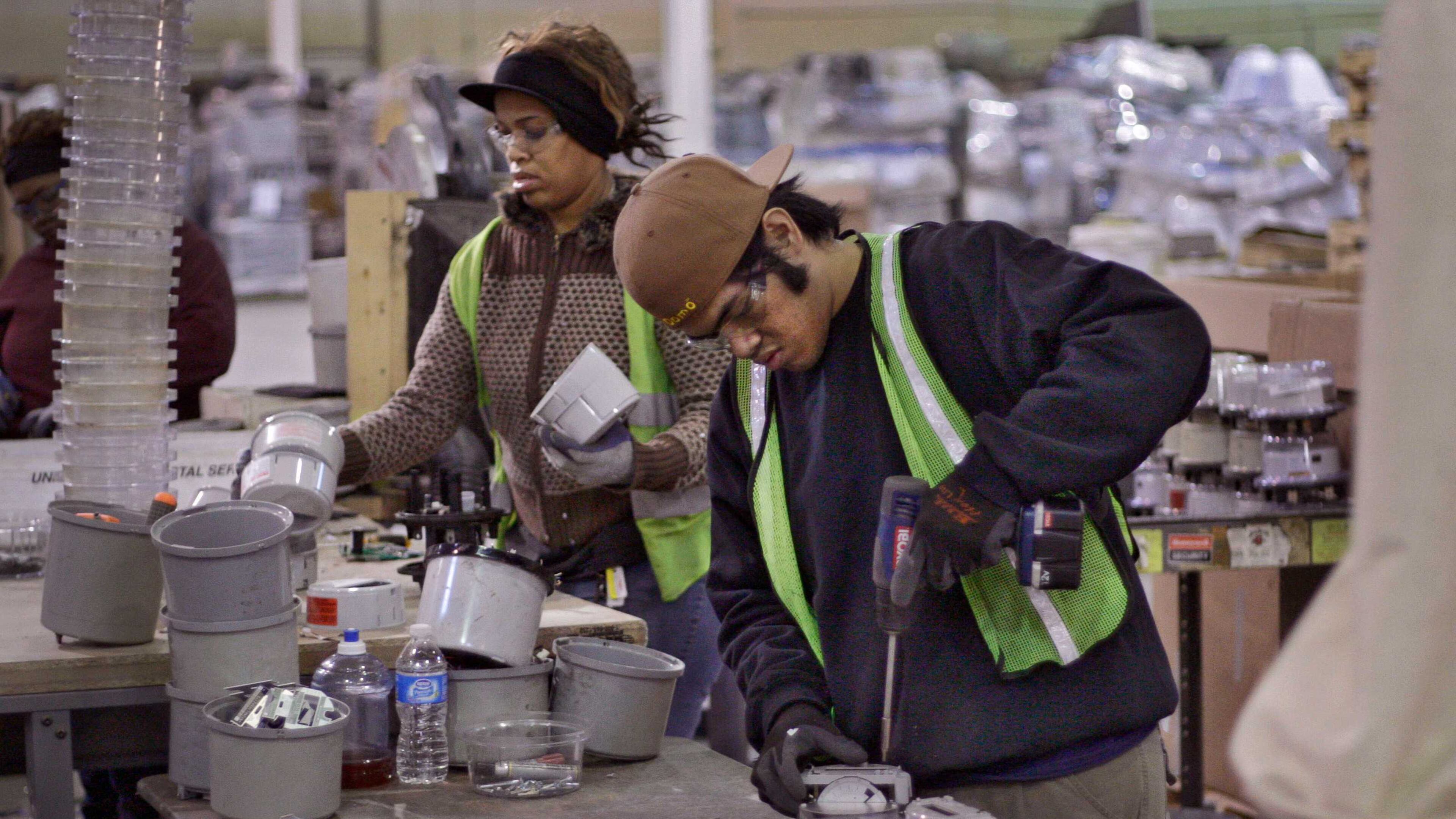 Tracey Lyons (left) and Christopher Napisa disassemble old Georgia Power electric meters at the Tommy Nobis Center. The vests indicate they are hearing impaired.