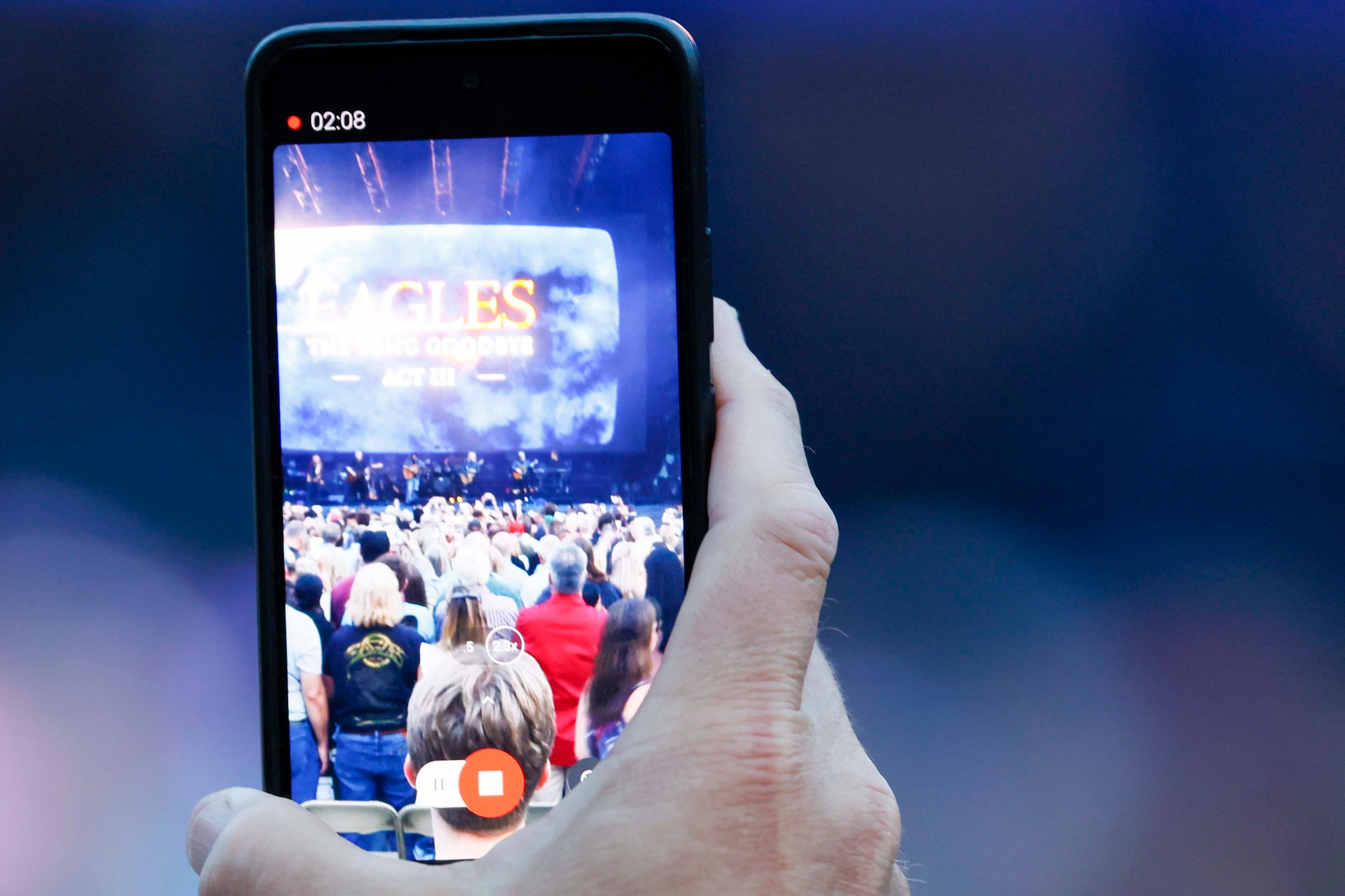 A fan films a video as the Eagles take the stage during the Long Goodbye Act III tour at Truist Park on Tuesday, May 5, 2026. (Miguel Martinez/AJC)