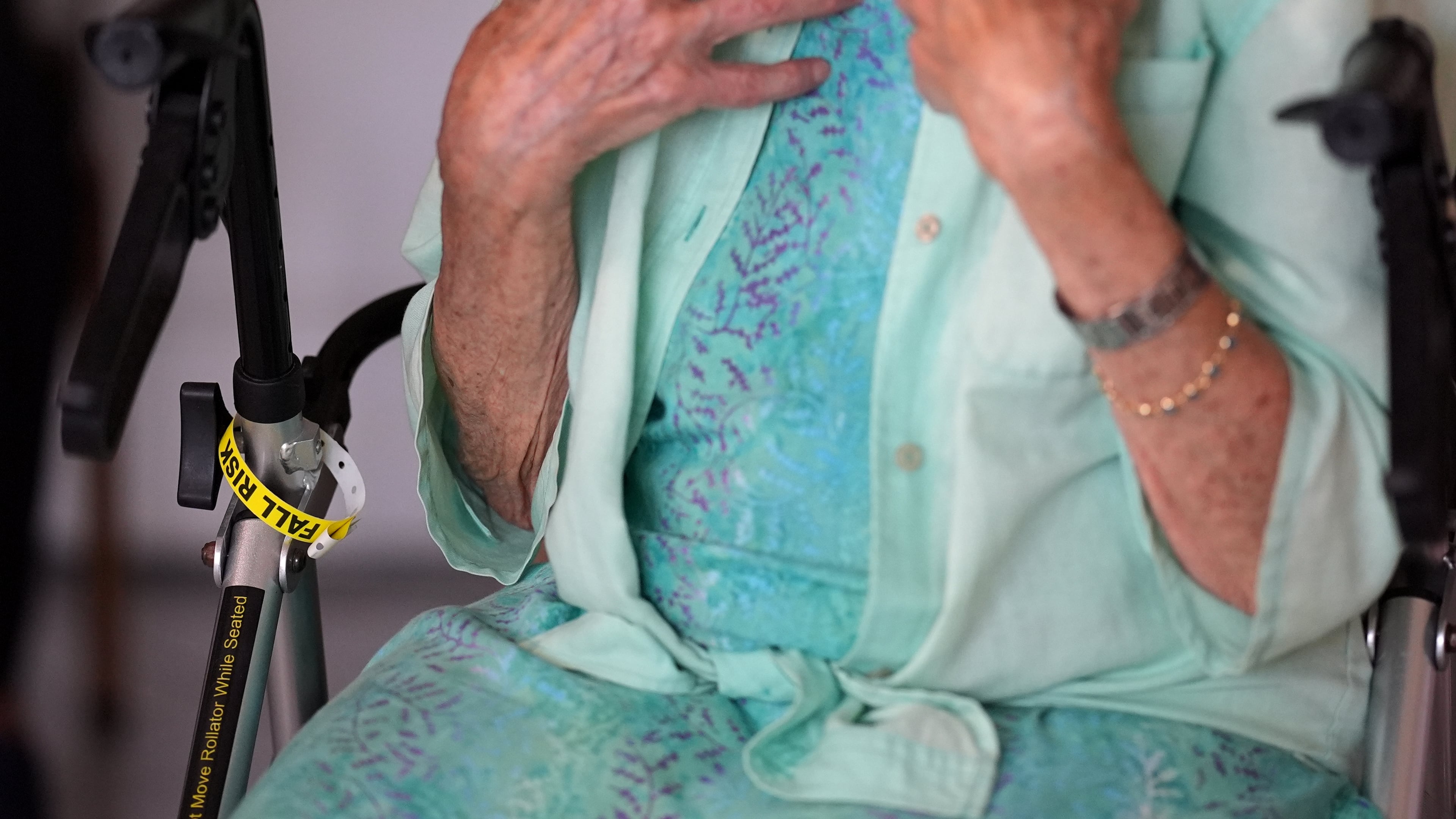 A "Fall Risk" alert bracelet marks the walker of Anna Fischbein as she speaks about the loss of a beloved Haitian home health care worker whose Temporary Protected Status expired this week, during an interview in her apartment, Thursday, July 30, 2026, in Sunny Isles Beach, Fla. (AP Photo/Rebecca Blackwell).
