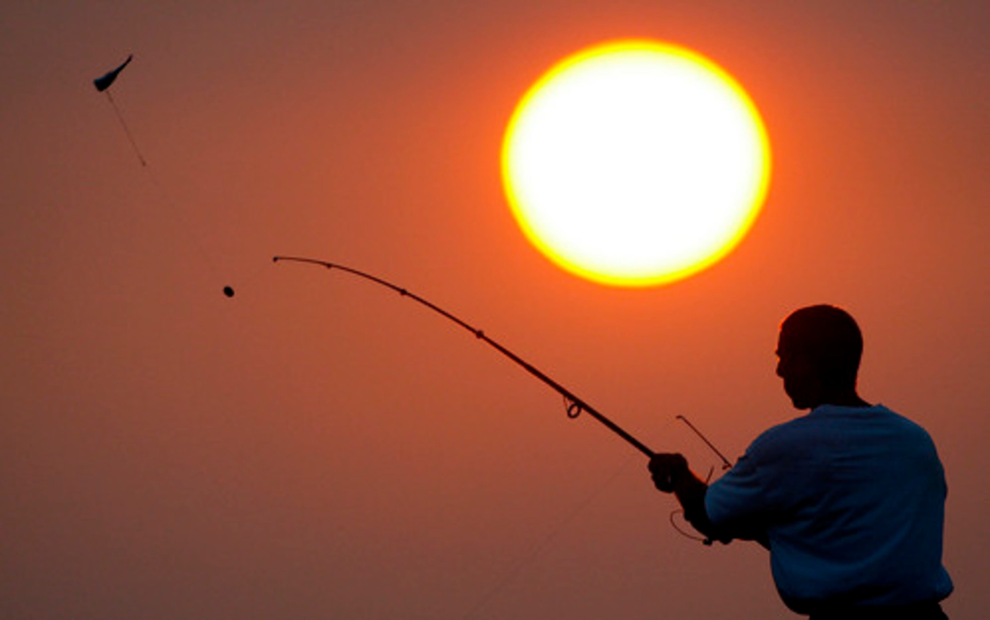 Silhouetted against an afternoon sunset, a fisherman casts his bait into the waters of St. Joe Bay in Port St. Joe, Fla.