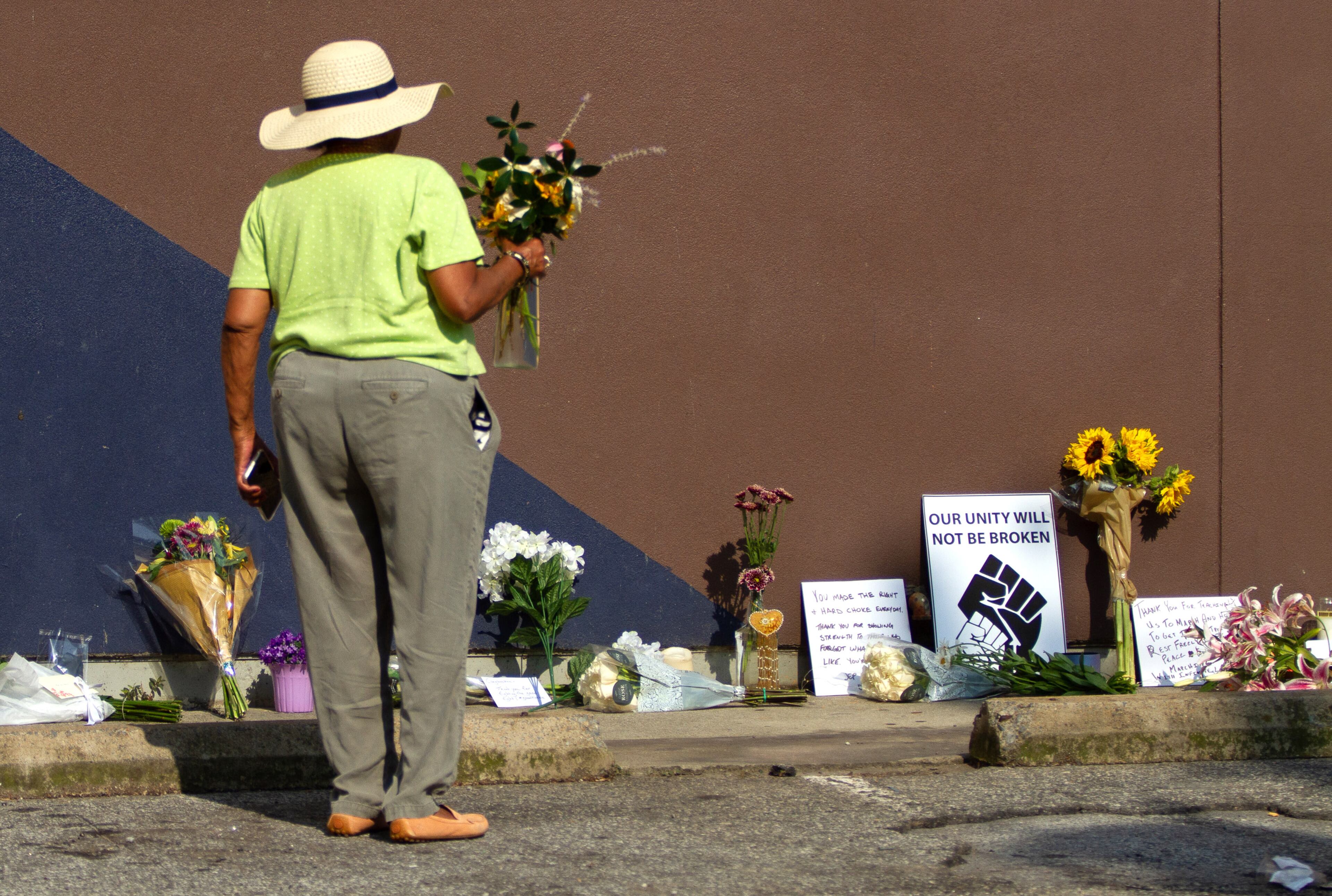 A woman looks for a place to put down her flowers under the large John Lewis mural on Auburn Avenue in Atlanta on Saturday, July 18, 2020. STEVE SCHAEFER FOR THE ATLANTA JOURNAL-CONSTITUTION