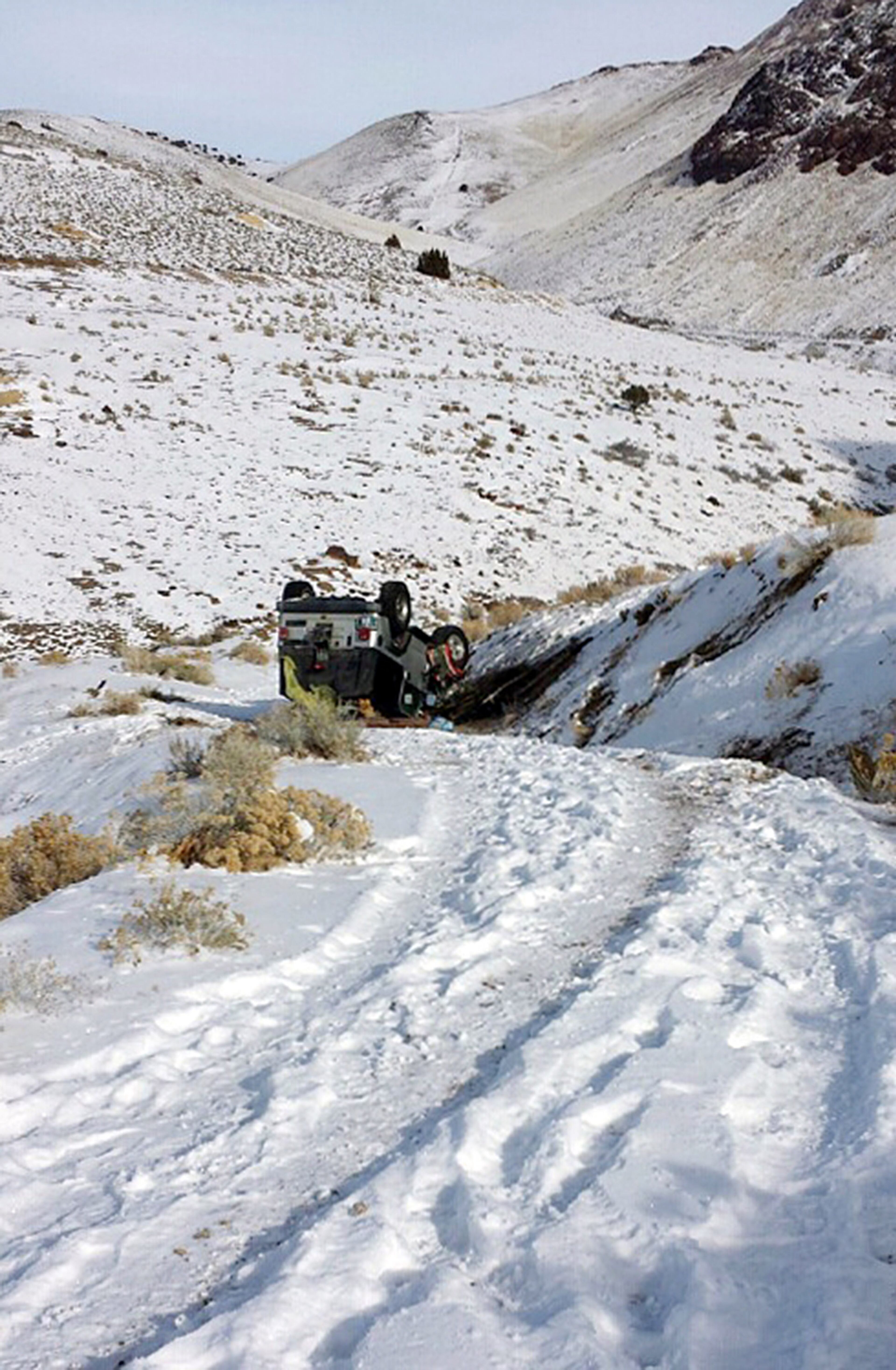 This Tuesday, Dec. 10, 2013 photo provided by searcher Lucia Gonzalez shows the vehicle belonging to a family who went missing after a trip to play in the snow near Lovelock, Nev. James Glanton, his girlfriend Christina McIntee, their two children and a niece and nephew of Christina McIntee, were missing since Sunday and were found by searchers on Tuesday. Their vehicle had overturned and they were stranded in weather that saw temperatures dip to 16 below zero. (AP Photo/Lucia Gonzalez)