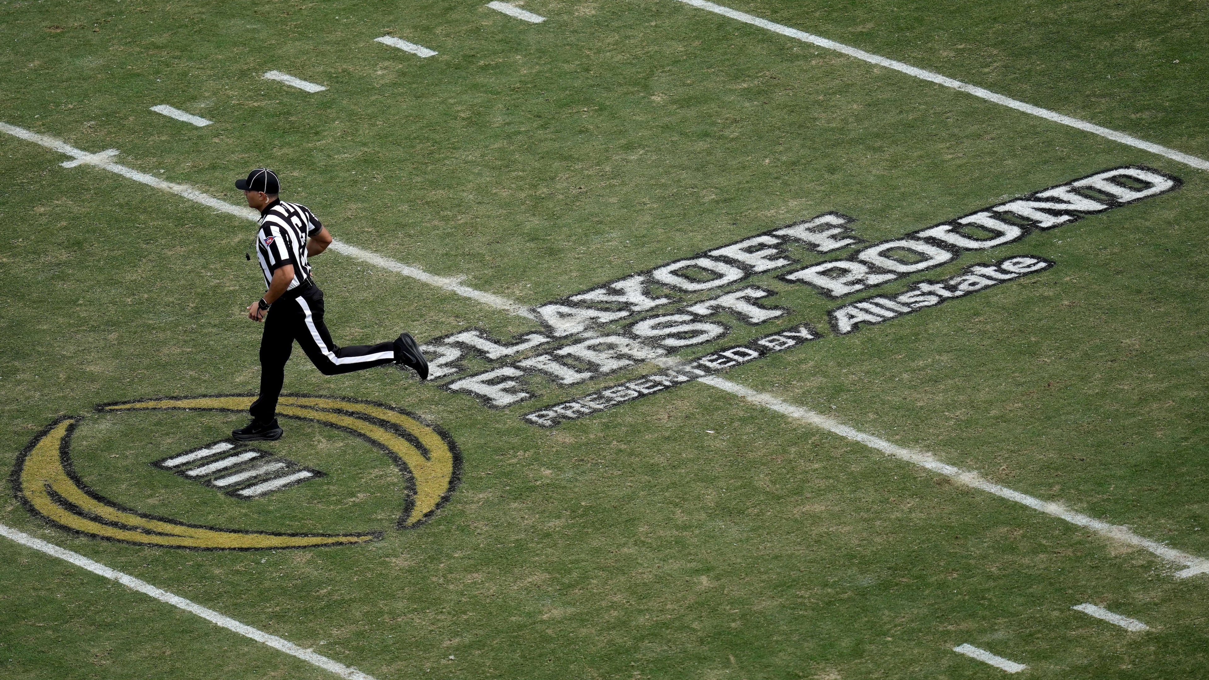 FILE - A game official runs across the College Football Playoff logo on Kyle Field during the third quarter in the first round of the College Football Playoff between Miami and Texas A&M, Dec. 20, 2025, in College Station, Texas. (AP Photo/Sam Craft, File)