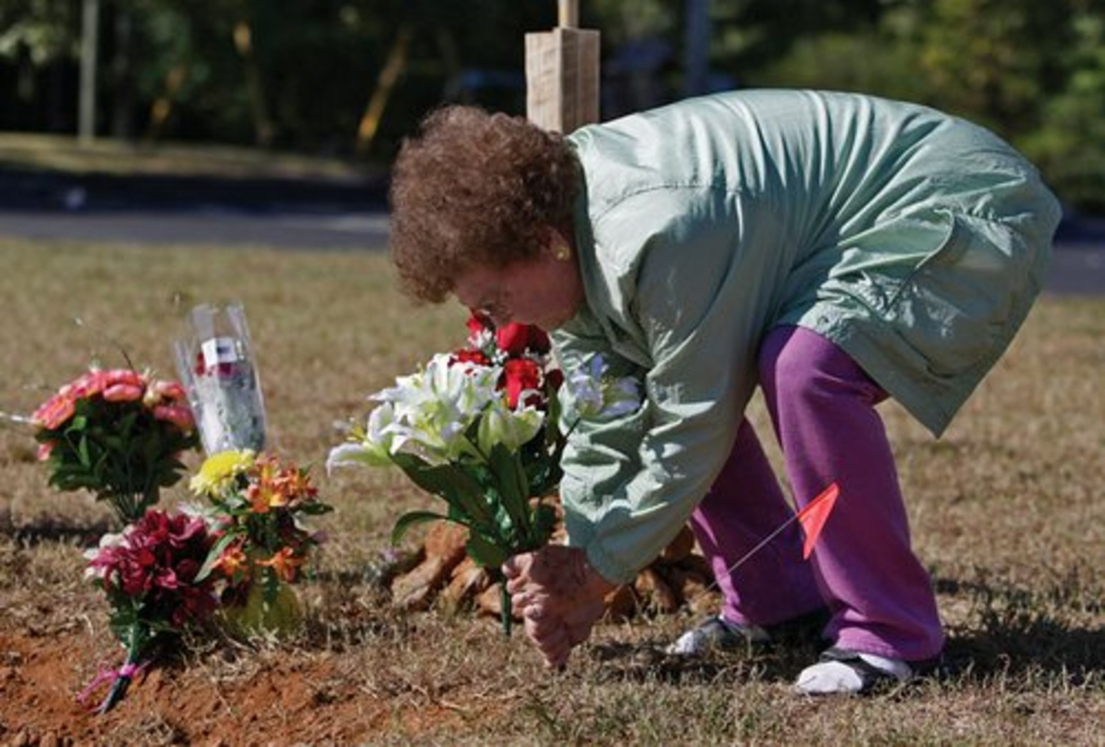 Lanell Burt places flowers at the site of the crash. She also baked some pies for the family of James Rashawn Walker and wanted to know where she could leave them.