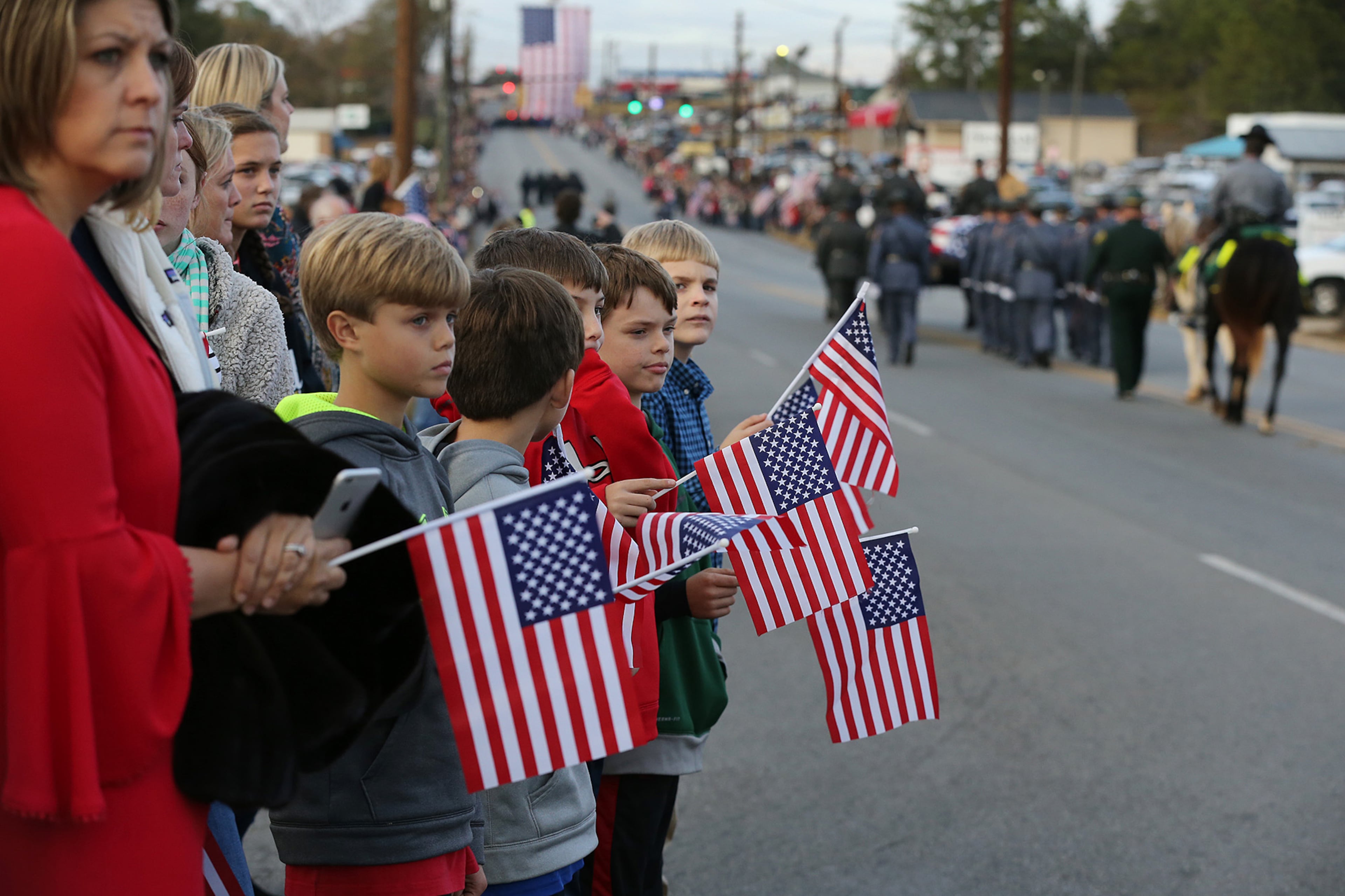 December 11, 2016, AMERICAS: Youngsters with American flags join thousands lining the street as the North Carolina Troopers Association/N.C. Highway Patrol Caison Unit pass by transfering Americus police officer Nicholas Ryan Smarr from his funeral service to Oak Grove Cemetery on Sunday, Dec. 11, 2016, in Americas. Officer Smarr and Georgia Southwestern State University campus police officer Jody Smith were killed responding to a domestic dispute. Curtis Compton/ccompton@ajc.com