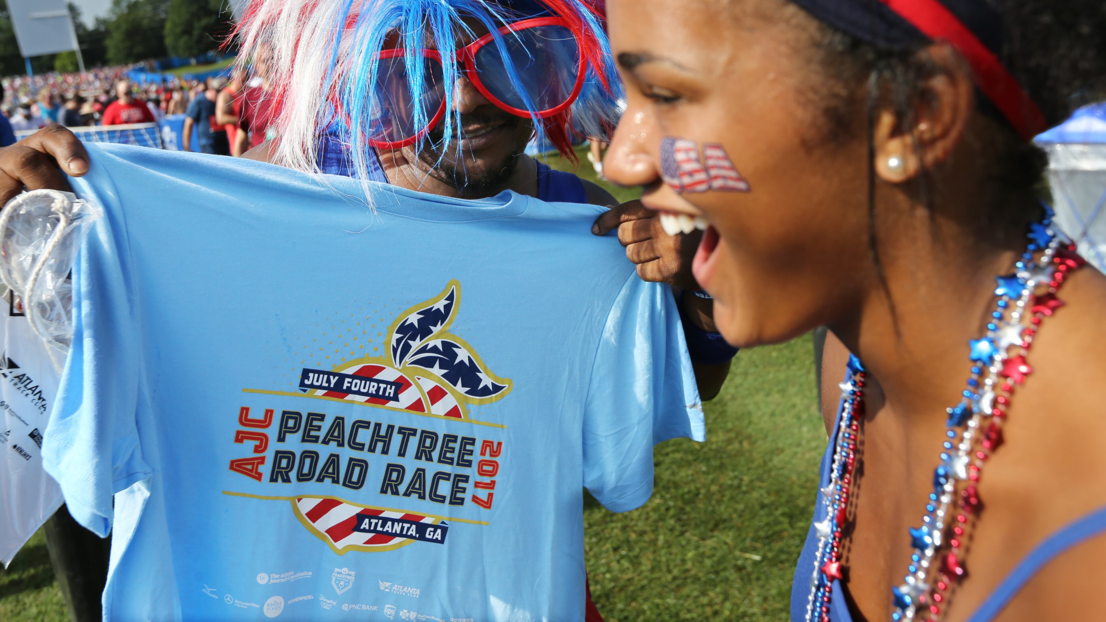 Vel Brooks, Acworth, checks out his hard earned T-shirt while his daughter Jadyn Brooks breaks into laughter after they finished the 48th running of the AJC Peachtree Road Race on Tuesday, July 4, 2017, in Atlanta. Curtis Compton/ccompton@ajc.com