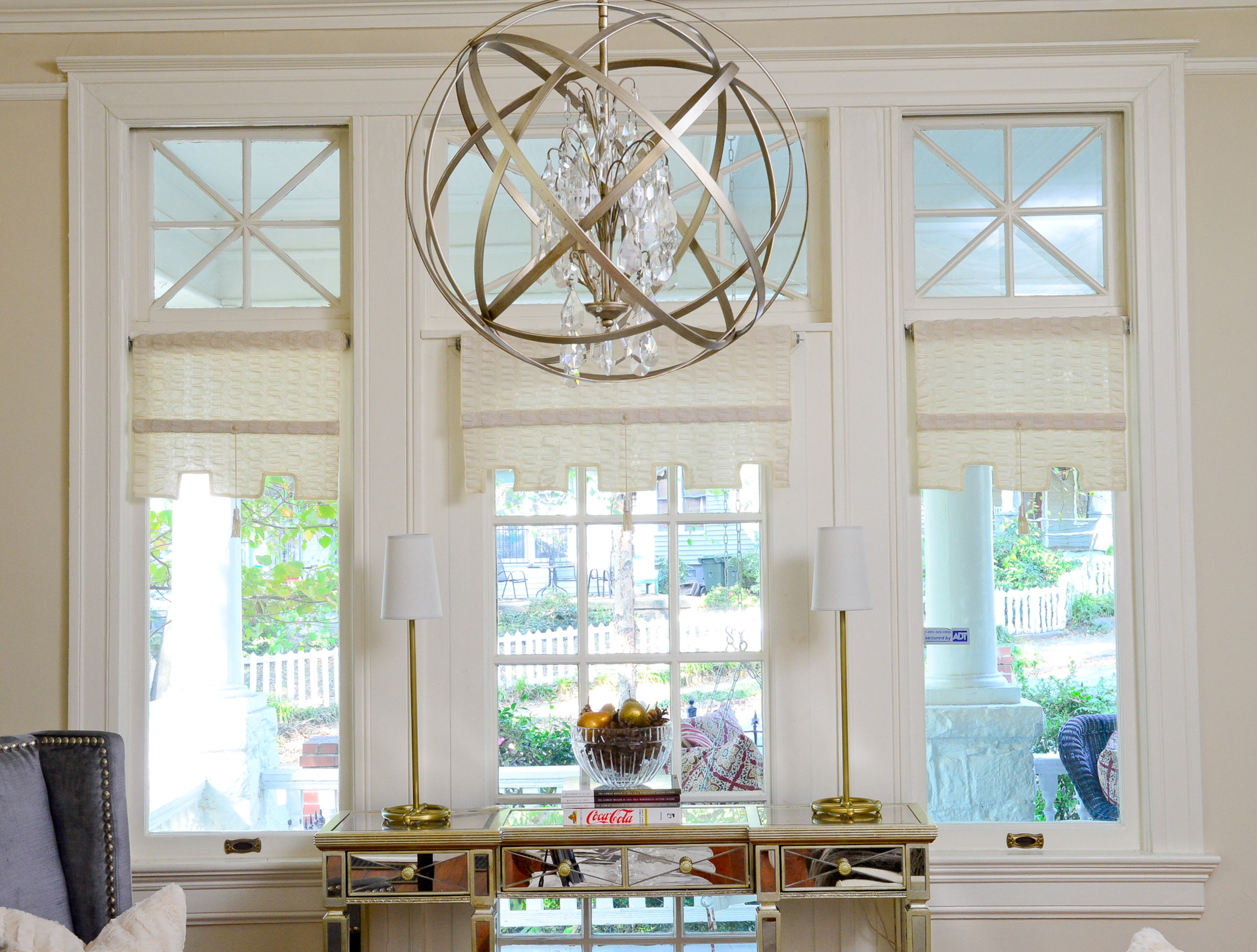 A mirrored console from Horchow reflects the furnishings in the living room, which looks out onto the deep front porch and Midtown neighborhood. The orb chandelier is from Capital Lighting Fixture Company.