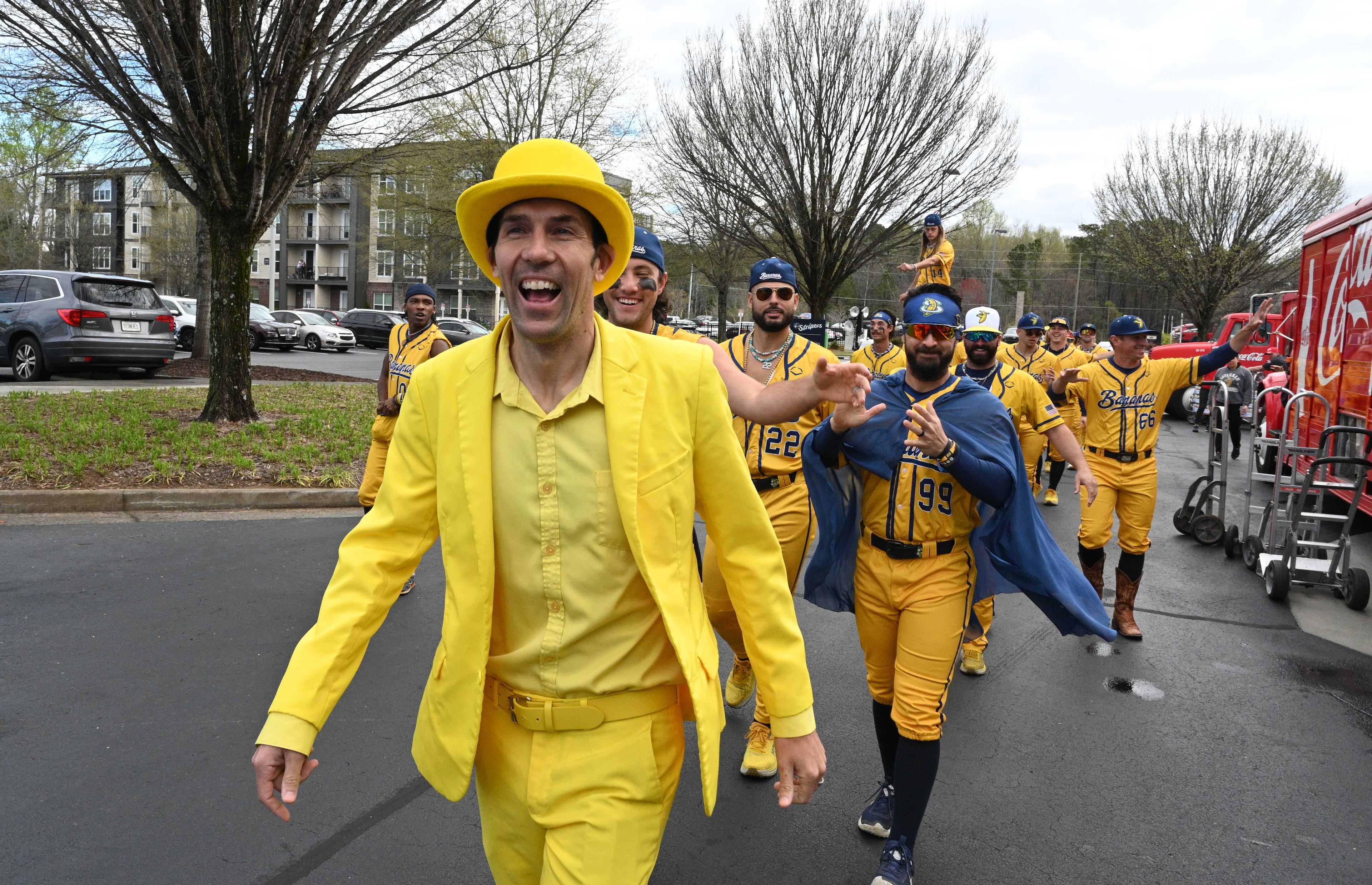 Savannah Bananas owner Jesse Cole and team members march through the parking lot before their first of three-game series at Coolray Field. (Hyosub Shin / Hyosub.Shin@ajc.com)