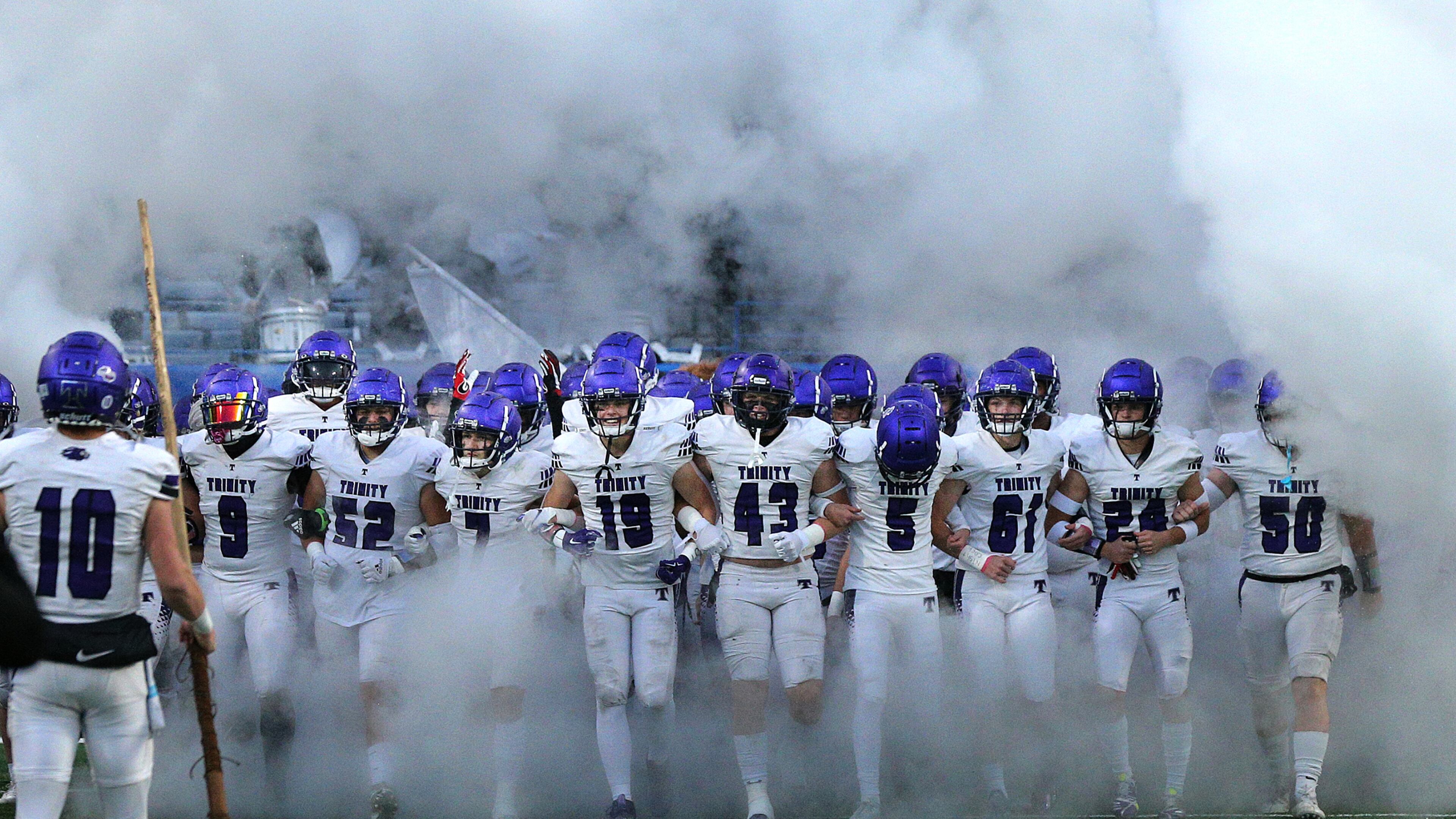 120921 Atlanta: Trinity Christian players take the field arm in arm to challenge the defending champions Prince Avenue Christian in their GHSA Class A Private Championship game on Thursday, Dec 9, 2021, in Atlanta. “Curtis Compton / Curtis.Compton@ajc.com”`