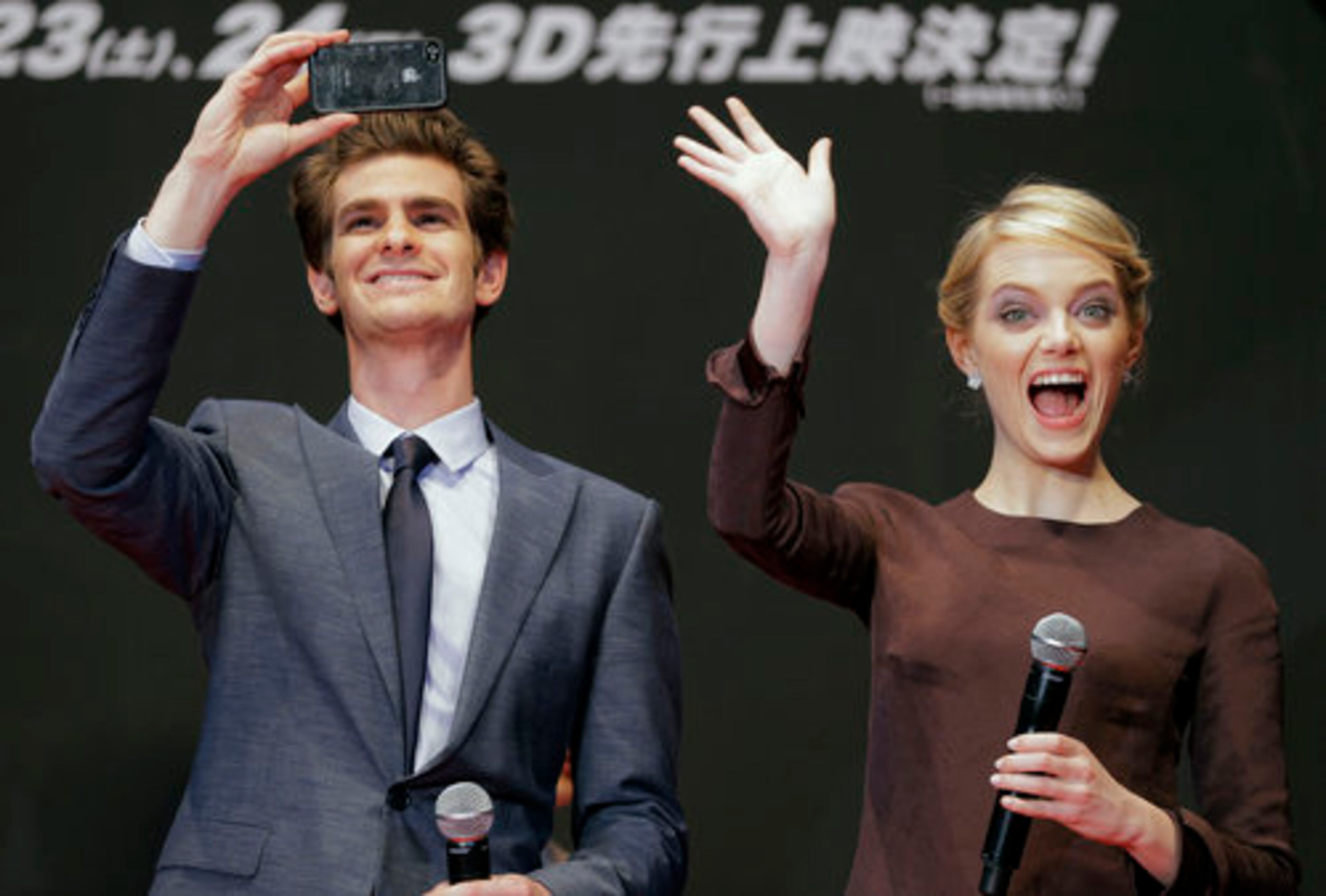 Andrew Garfield, who replaces Tobey Maguire in the role of Peter Parker/Spider-Man, snaps a shot of the crowd as co-star Emma Stone gives an enthusiastic hello.