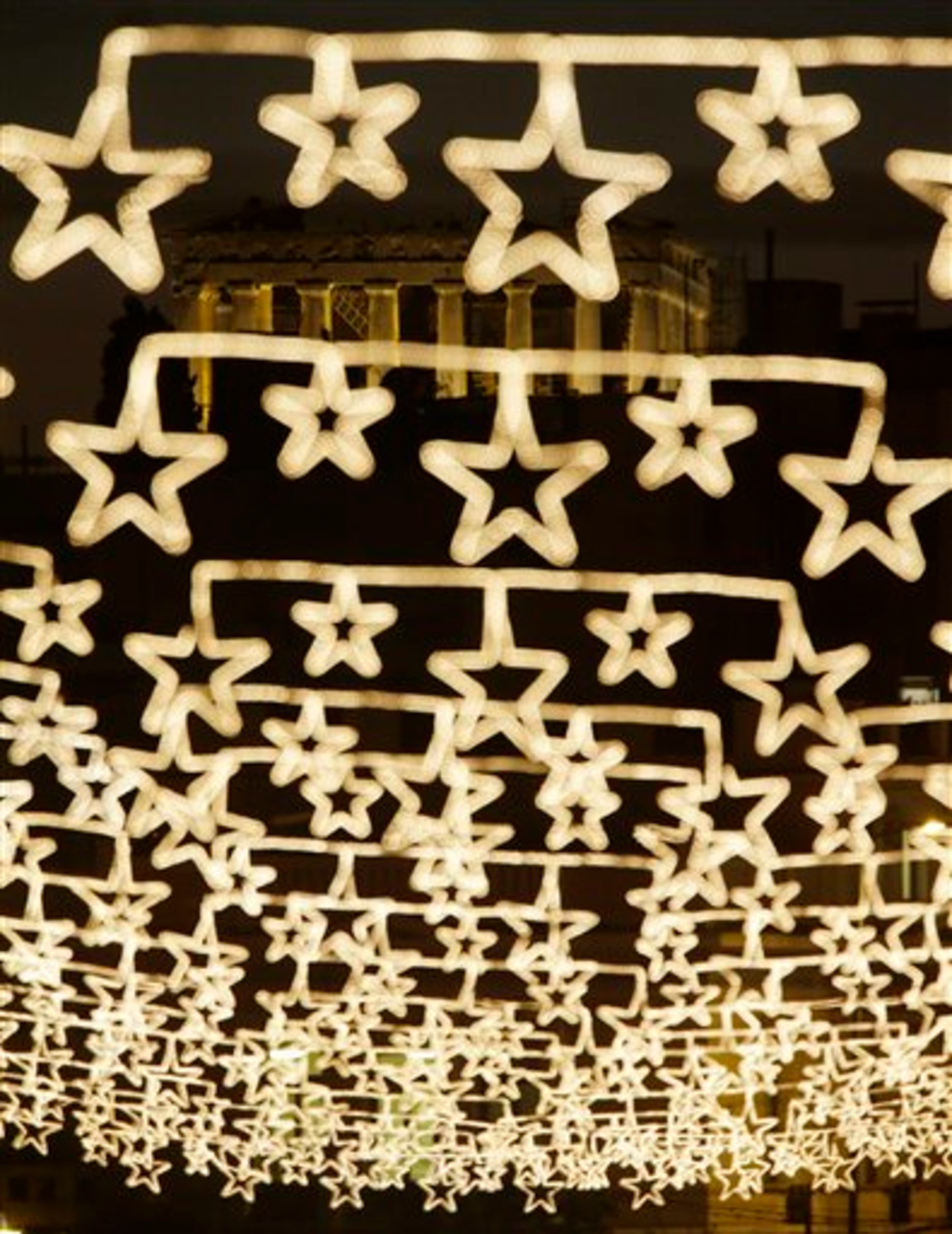 The Doric columns of the floodlit, 5th Century BC Parthenon Temple on the Acropolis appear behind strings of Christmas street lights in Athens, on Thursday, Dec. 18, 2014. This year's Christmas and New Year celebrations in financially struggling Greece are overshadowed by a threatened political crisis, sparked by the election of the country's new president. The conservative-led government failed Wednesday to secure enough support for its nominee, and if the same happens in two more rounds of voting by Dec. 29, early national elections will have to be called just as the country is crawling out of a punishing six-year recession. (AP Photo/Thanassis Stavrakis)