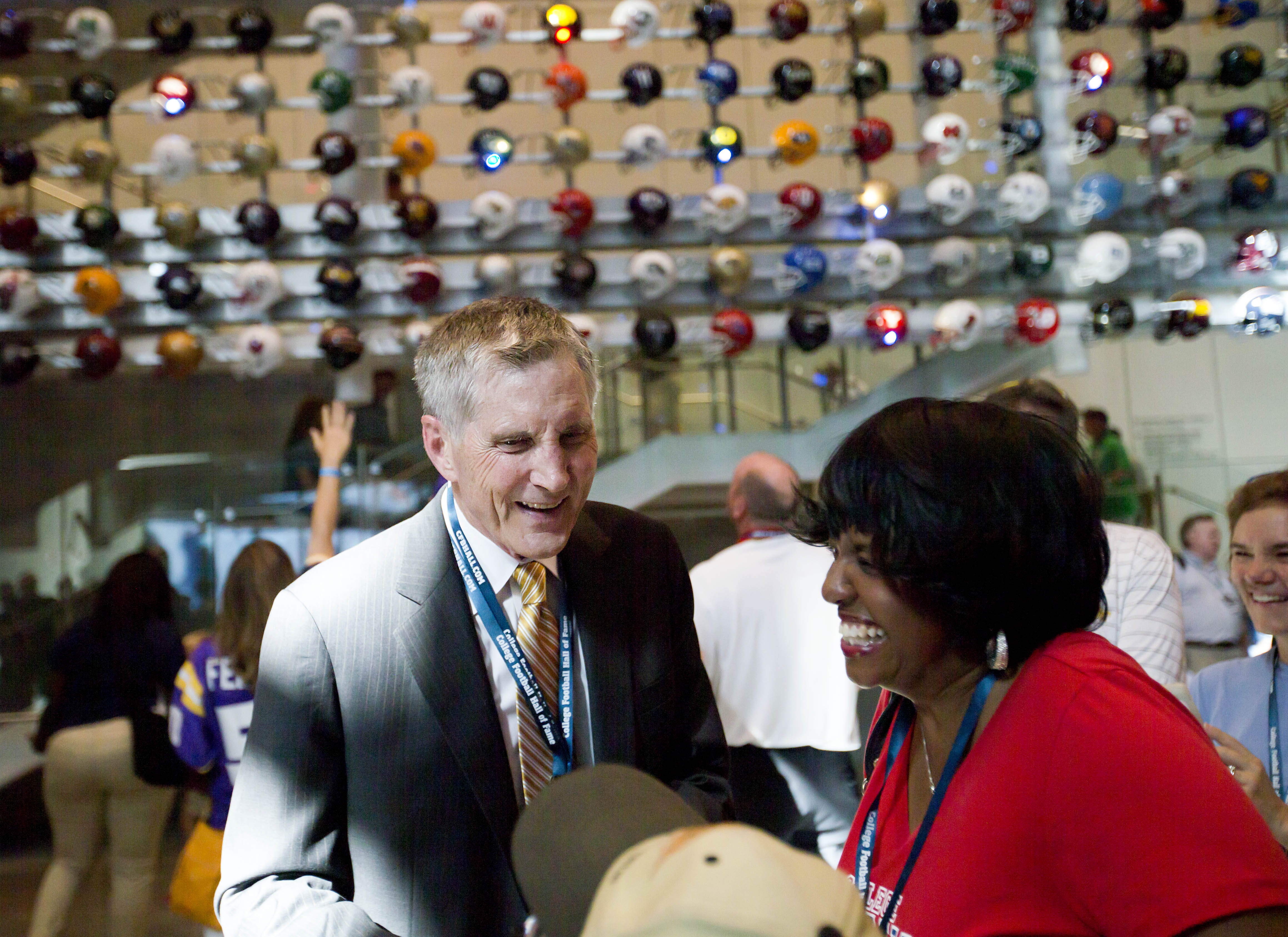 Former Georgia Tech, Alabama, Kentucky and Georgia State football coach, Bill Curry, left, greets visitors at the College Football Hall of Fame grand opening, Saturday, Aug. 23, 2014, in Atlanta. The new high-tech hall features an interactive experience that begins when the guest registers for a smart pass, selects a favorite school and then sees that school's helmet illuminated. (AP Photo/David Goldman)