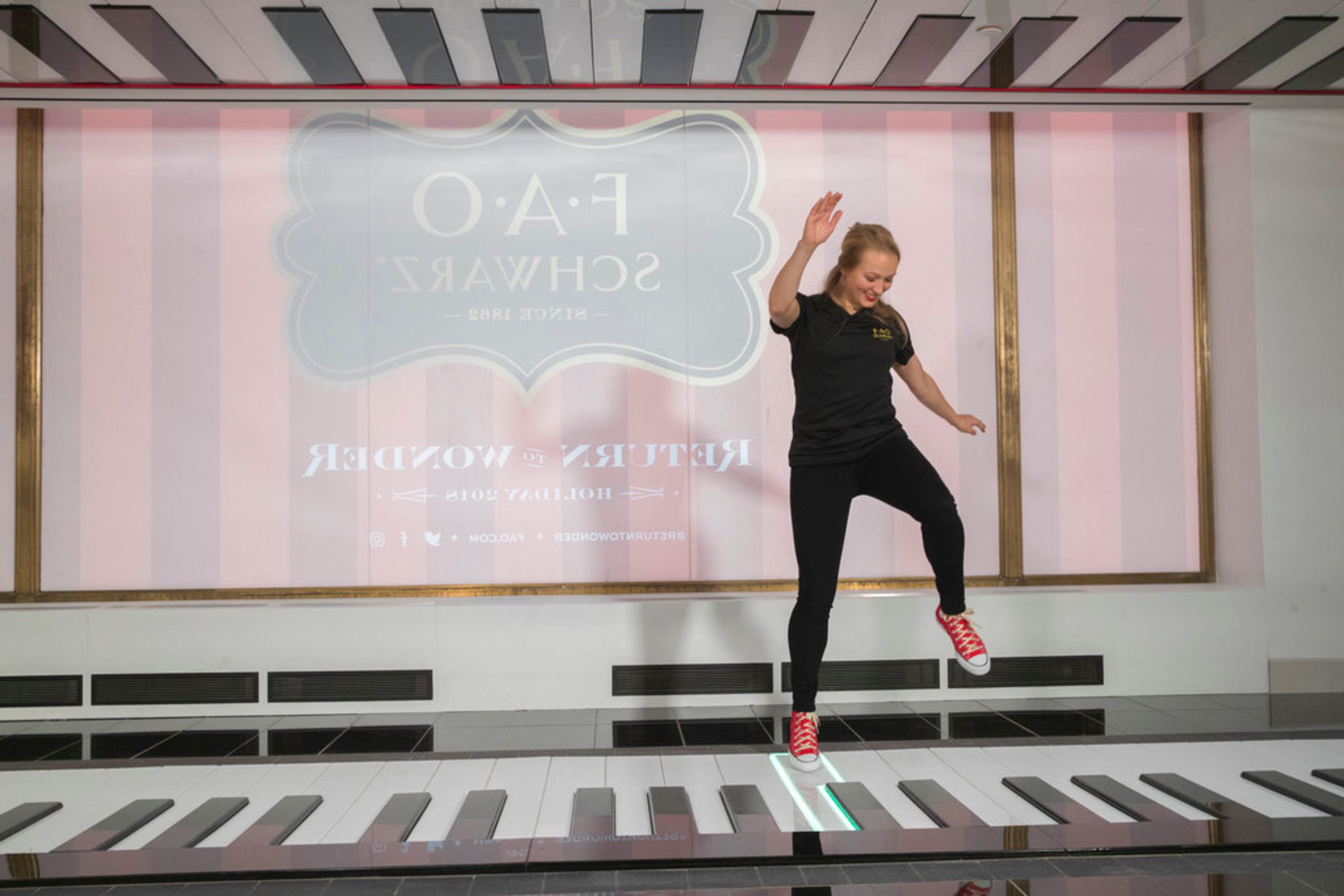 In this Tuesday, Nov. 13, 2018 photo, an employee plays the FAO Premium Piano Dance Mat during a media preview of the new FAO Schwarz store at Rockefeller Center in New York. Three years after it closed its beloved, fantasy land of a toy store on Fifth Avenue, FAO Schwarz makes its return to New York City. The new version will be smaller, but will have familiar attractions including a musical clock tower and the giant piano keyboard mat on which Tom Hanks danced in the film âBig.â (AP Photo/Mary Altaffer)