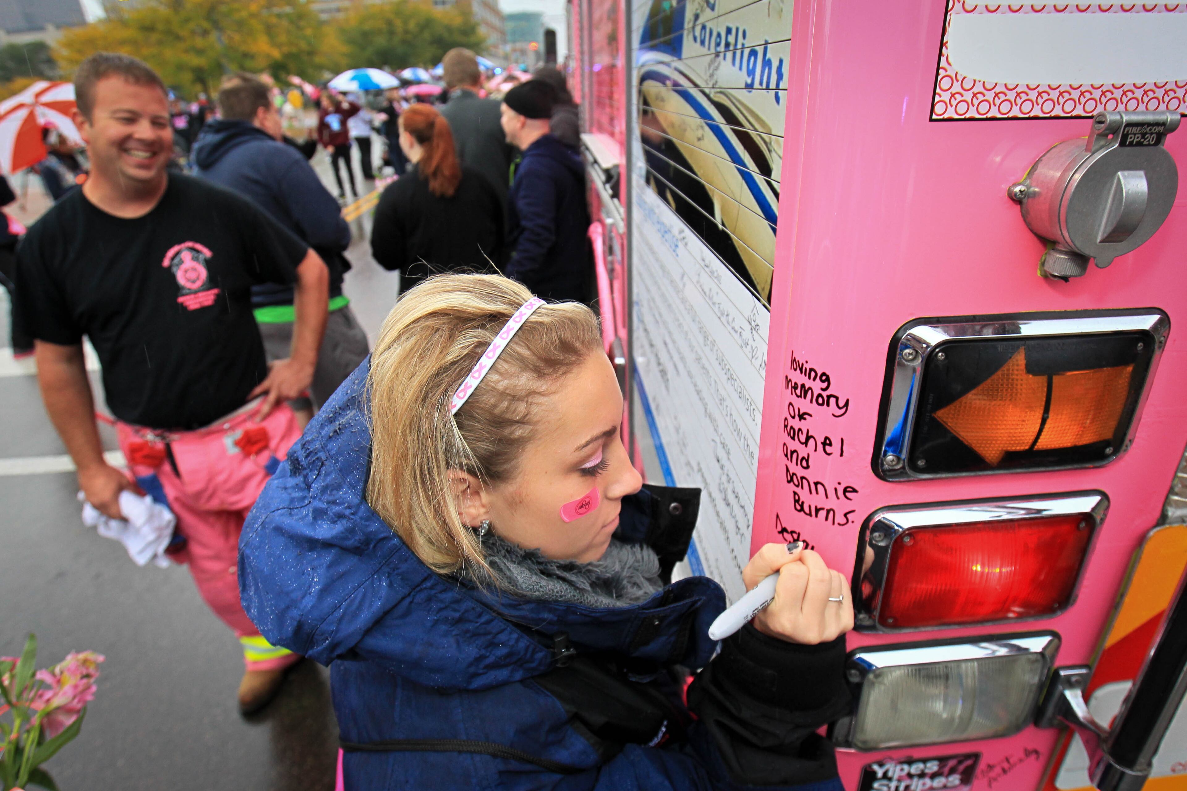 Participant Destanity (cq) McNeil signs the pink Huber Hts. Fire Engine Number 24 in memory of her grandparents at the Making Strides Against Breast Cancer Walk in Dayton at Fifth Third Field Saturday morning. JIM WITMER / STAFF
