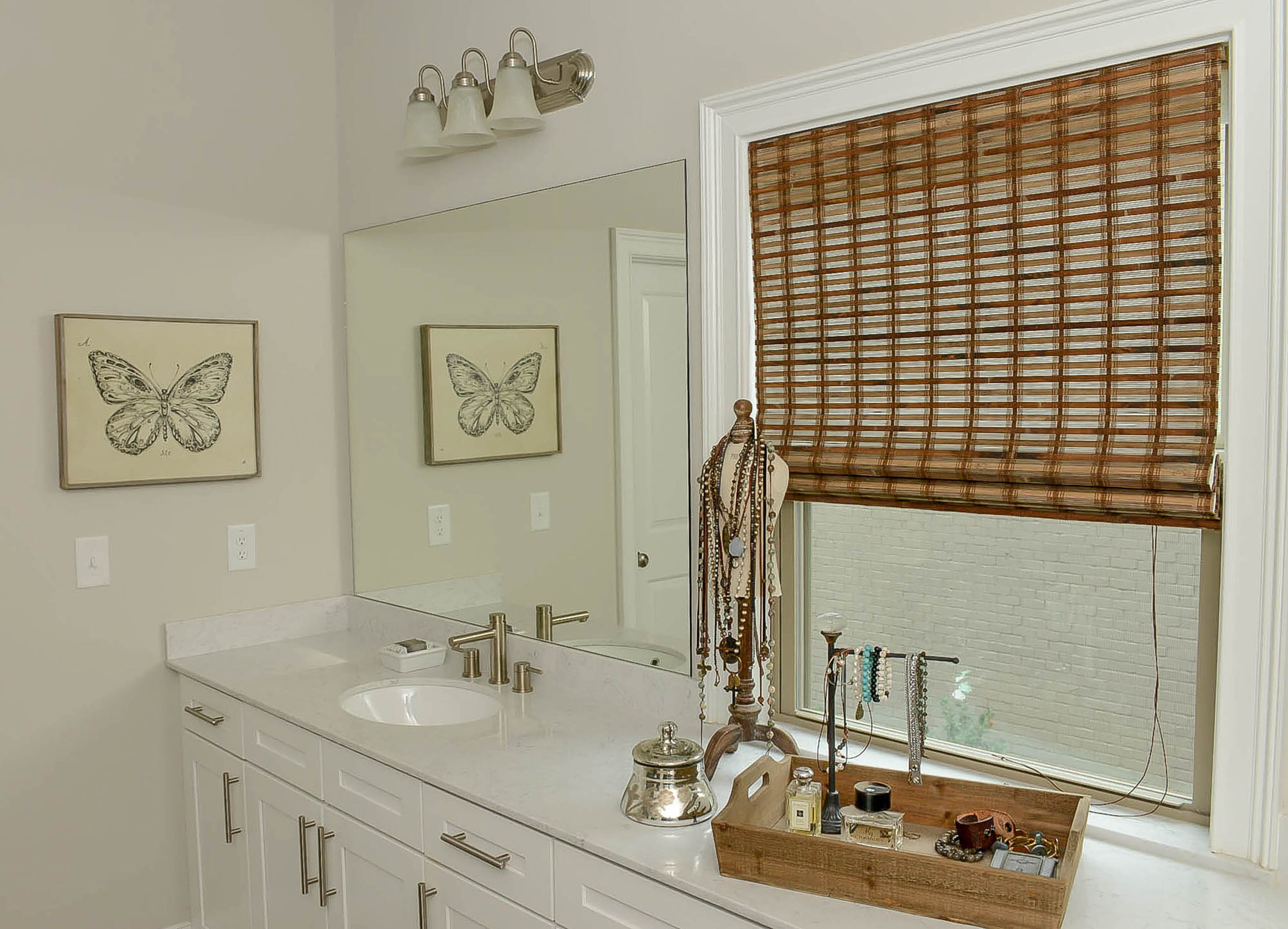 Keeping with the neutral theme throughout the home, these woven blinds and wooden jewelry tray rely on natural texture to give the space depth.