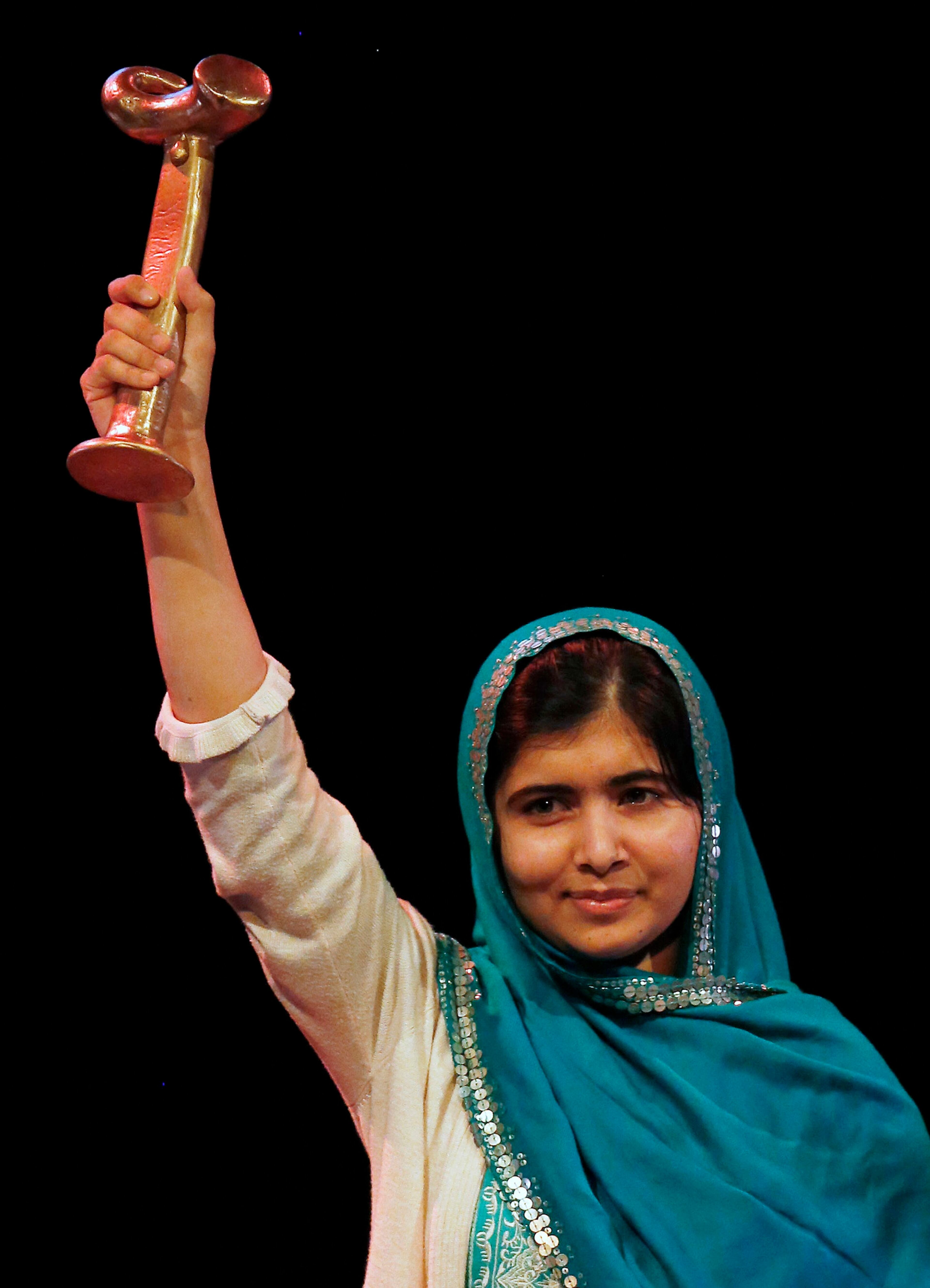 Pakistan's Malala Yousafzai raises the RAW (Reach All Women) in War Anna Politkovskaya Award after receiving it at the Southbank Centre in London October 4, 2013. The award is presented to a female human rights defender from a conflict who stands up for victims at their own personal risk.