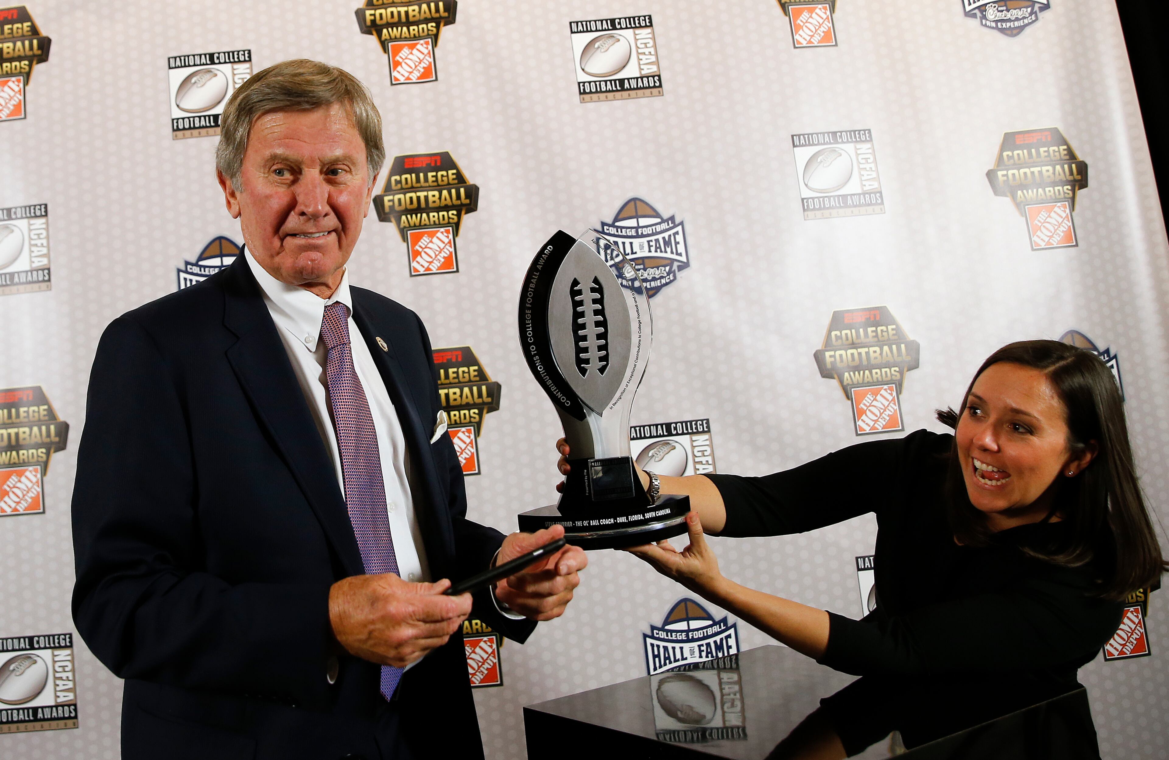 Former coach Steve Spurrier gets help taking a photo of the trophy after being awarded the NCFAA Contributions to College Football Award Thursday, Dec. 8, 2016, in Atlanta. (AP Photo/John Bazemore)