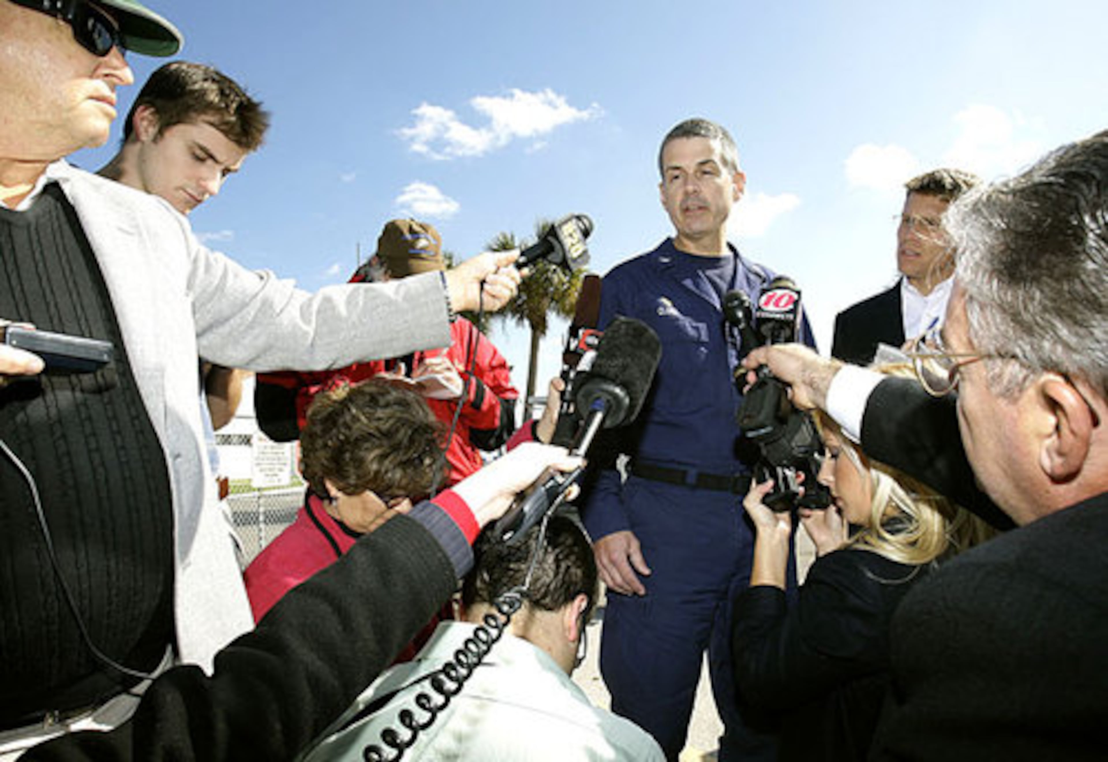 U.S. Coast Guard Captain Timothy Close, center, briefs the media about the rescue and continuing search.