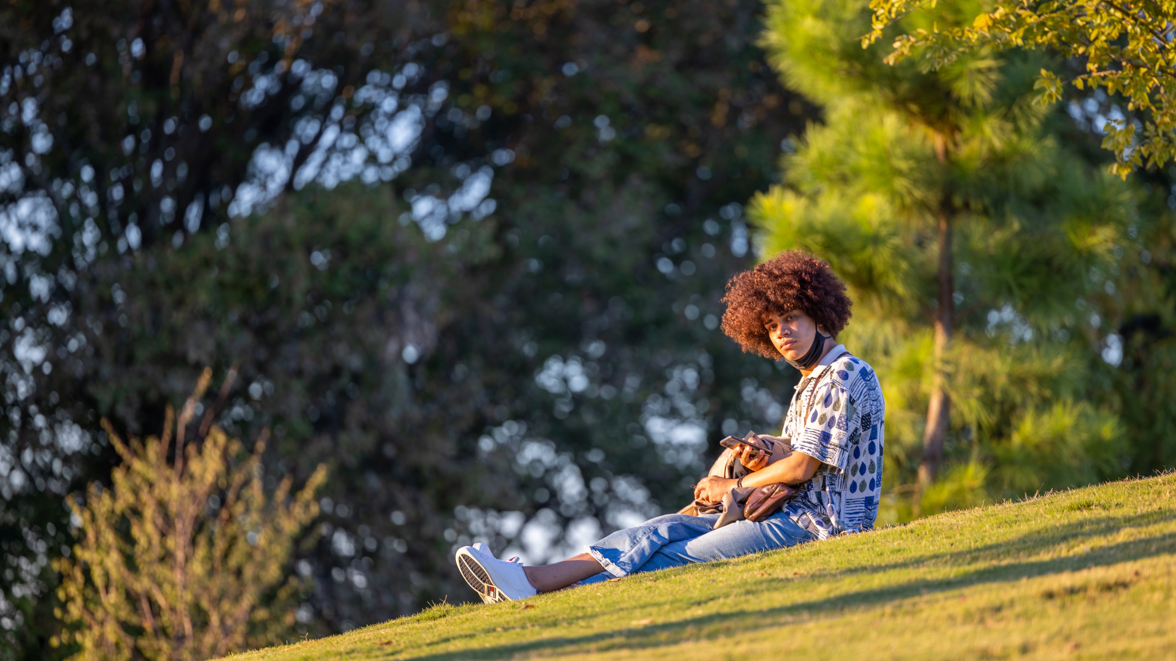 Man sitting in field using his phone at Westside Reservoir Park on October 6, 2022
