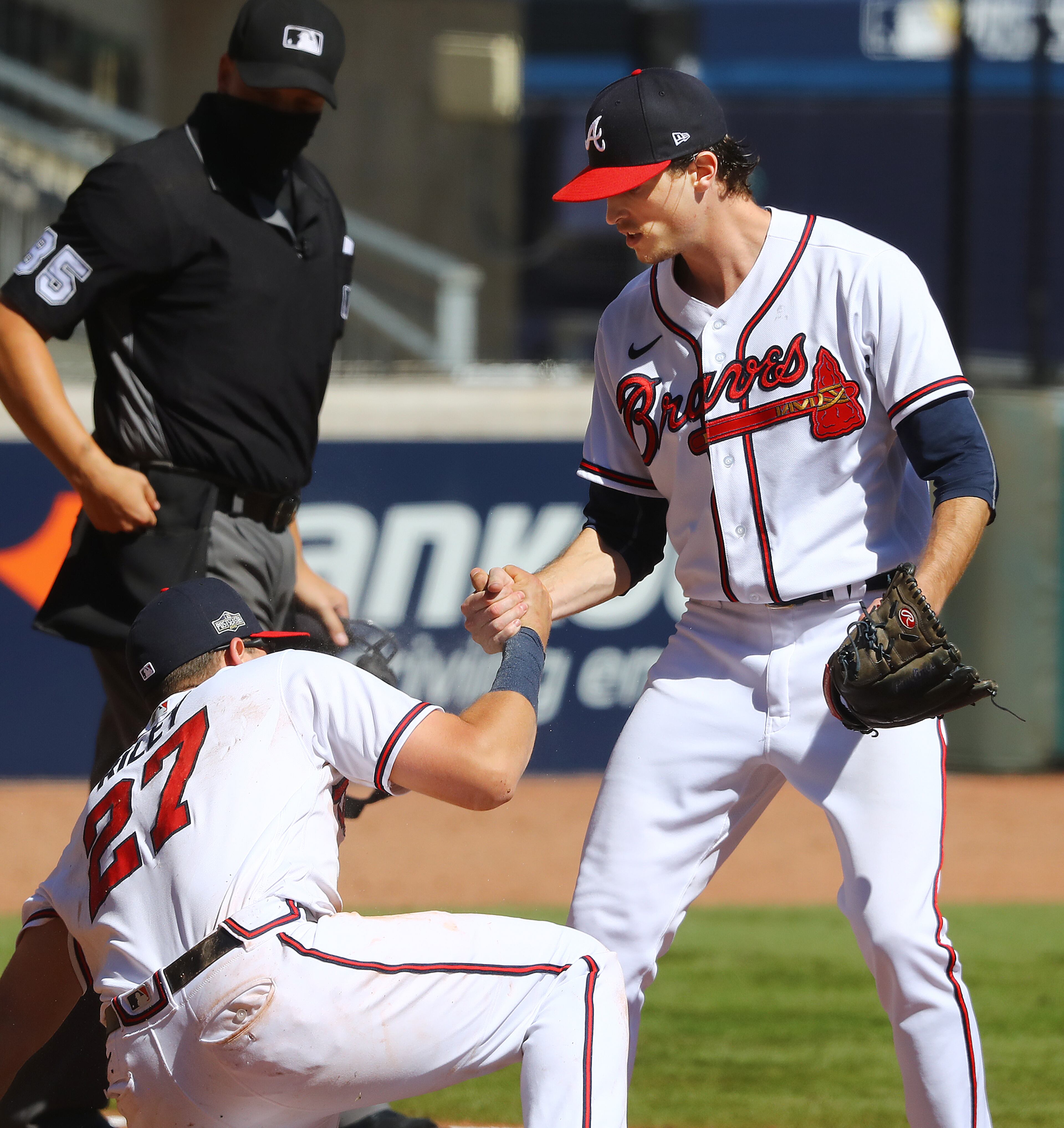 093020 Atlanta: Braves pitcher Max Fried gives third baseman Austin Riley a hand up after he tagged Reds Aristides Aquino out in a run down between third and home preventing a run from scoring during the 7th inning in game 1 in the National League wild card playoff series on Wednesday, Sept. 30, 2020 in Atlanta. “Curtis Compton / Curtis.Compton@ajc.com”