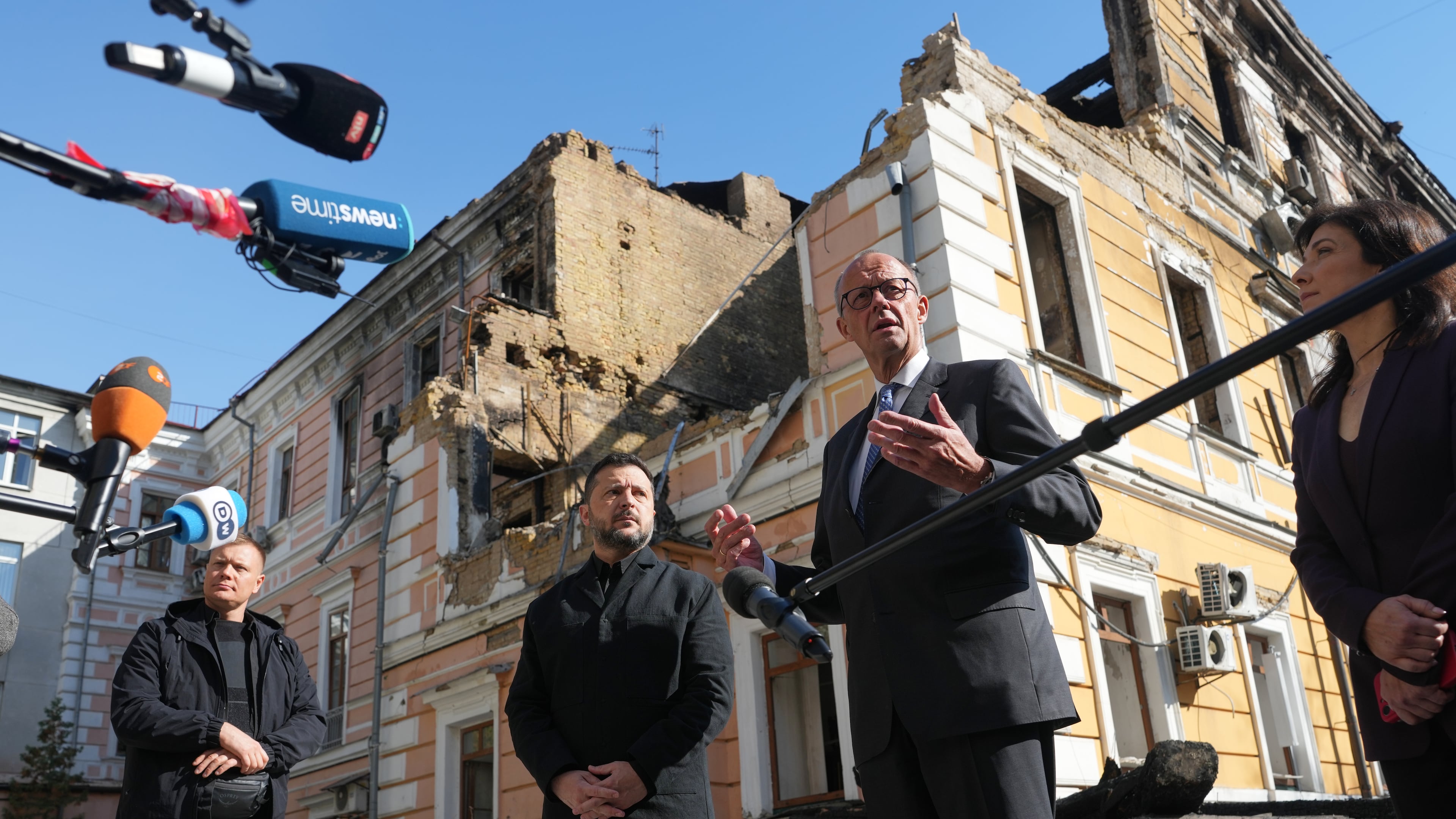 Ukraine's President Volodymyr Zelenskyy, centre, and German Chancellor Friedrich Merz speak to media with National Academy of science building damaged after a Russian drone strike, on the background, Kyiv, Ukraine, Sunday, Oct. 4, 2026. (AP Photo/Evgeniy Maloletka)