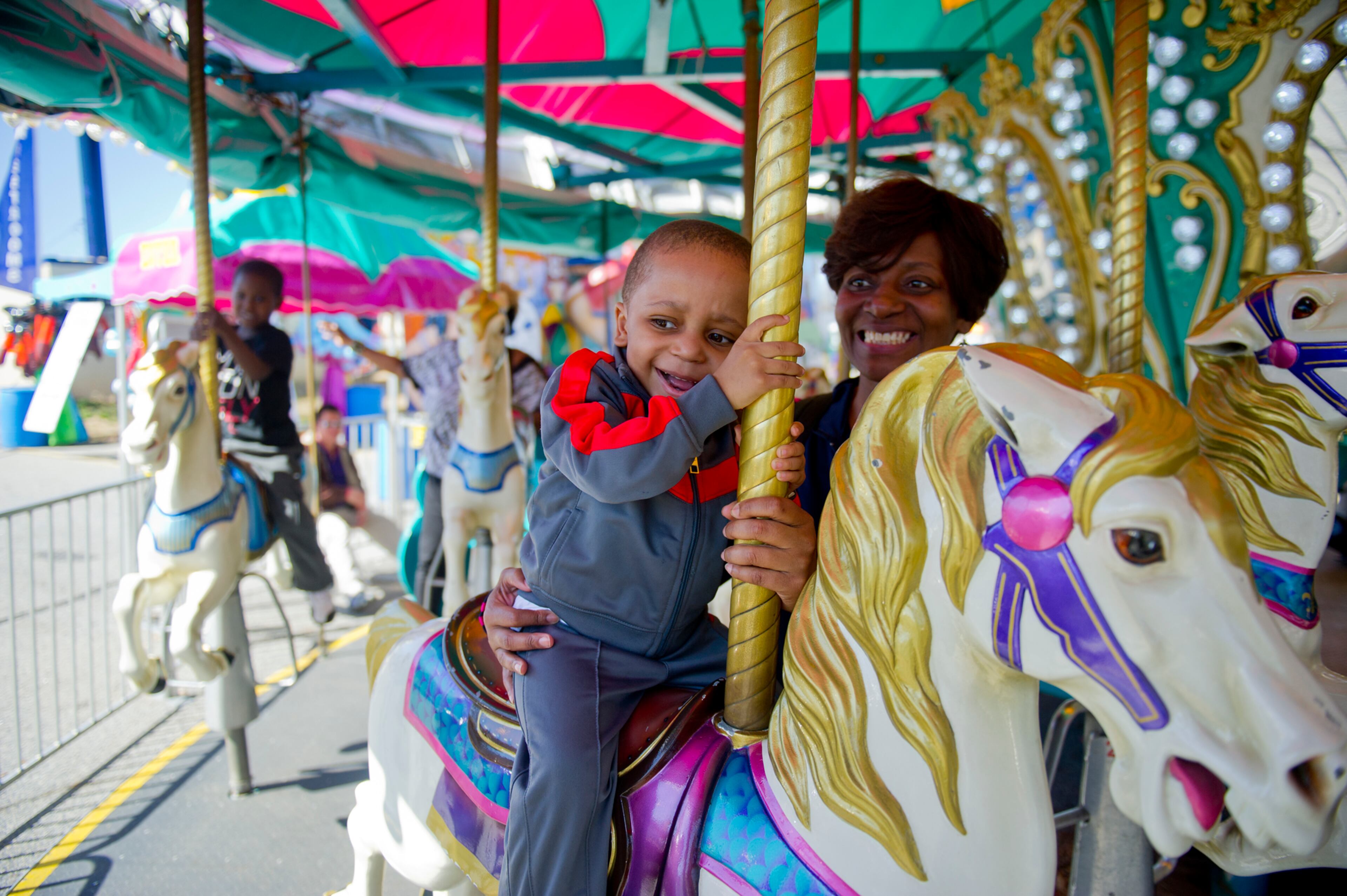 Jonah Isler (center) rides the merry-go-round with his mother Tanja during the Atlanta Fair at Turner Field on Saturday, March 8, 2014. The fair, which runs through April 6, has games, food and nearly 30 different rides.