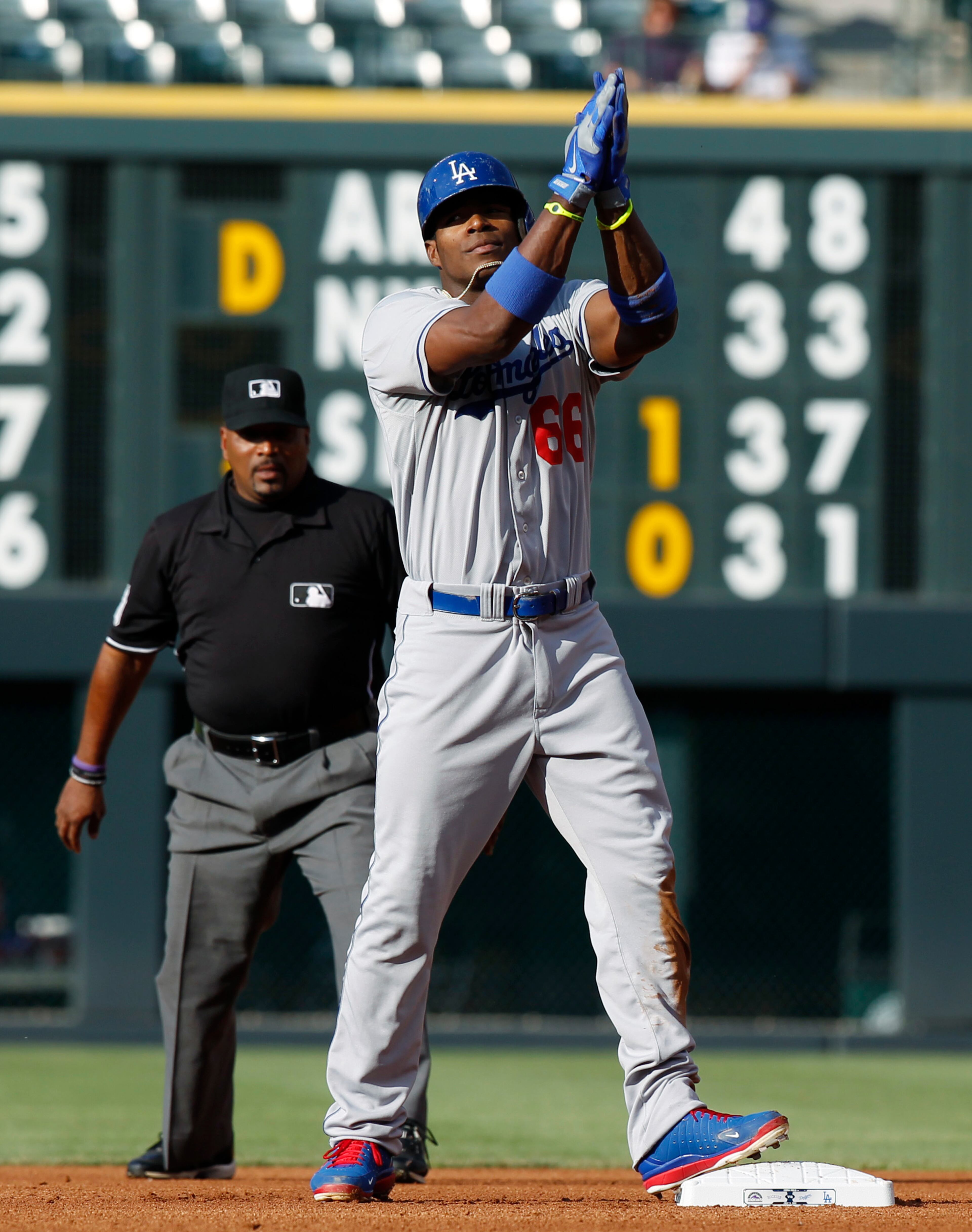 Los Angeles Dodgers' Yasiel Puig, right, celebrates after hitting a double against the Colorado Rockies in the first inning of a baseball game in Denver, Wednesday, July 3, 2013. (AP Photo/David Zalubowski)