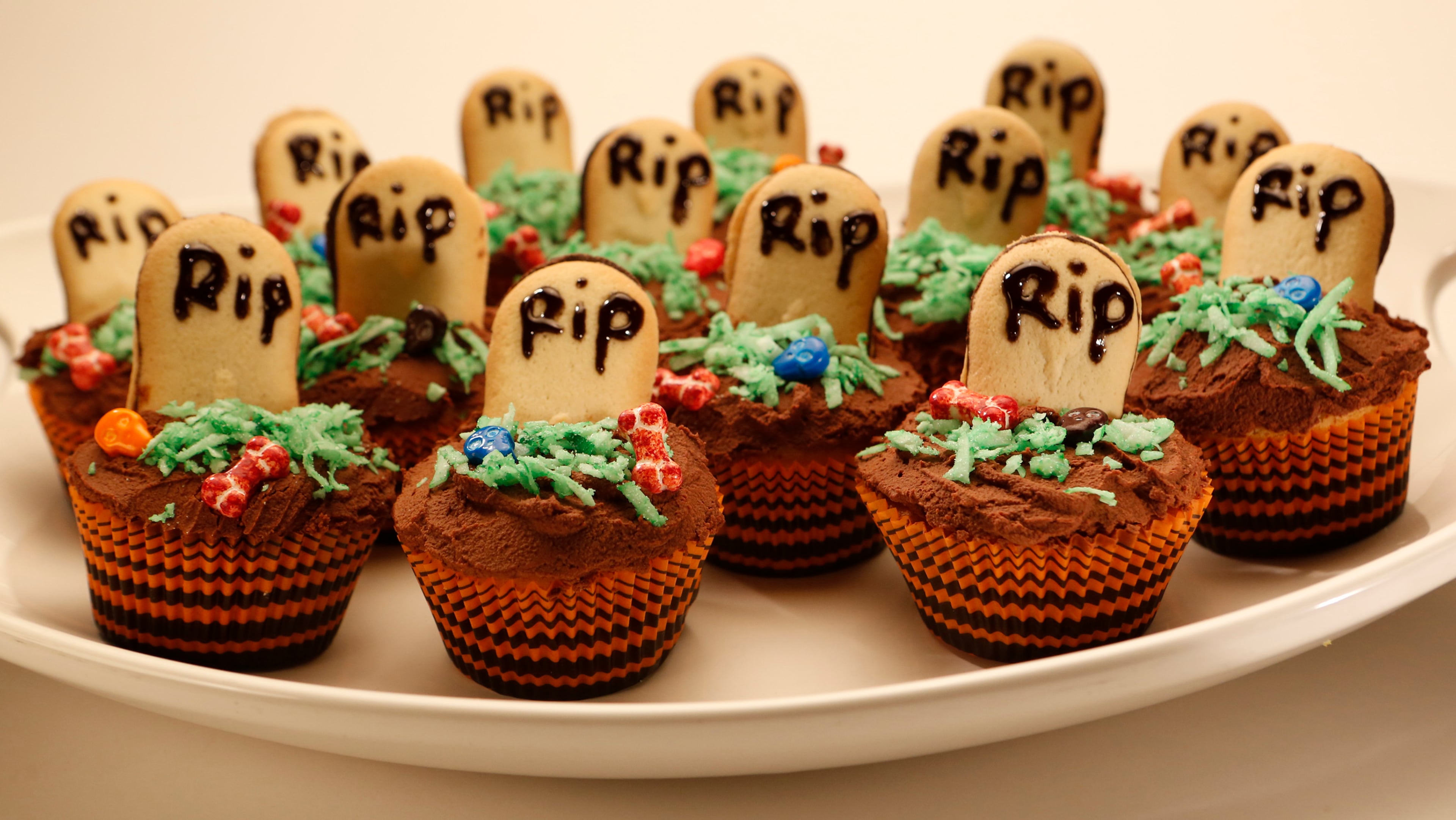 For graveyard cupcakes, frost the cakes with rich chocolate ganache and decorate with cookie "tombstones," colored coconut and bone-shaped candies. (Anne Cusack/Los Angeles Times/MCT)