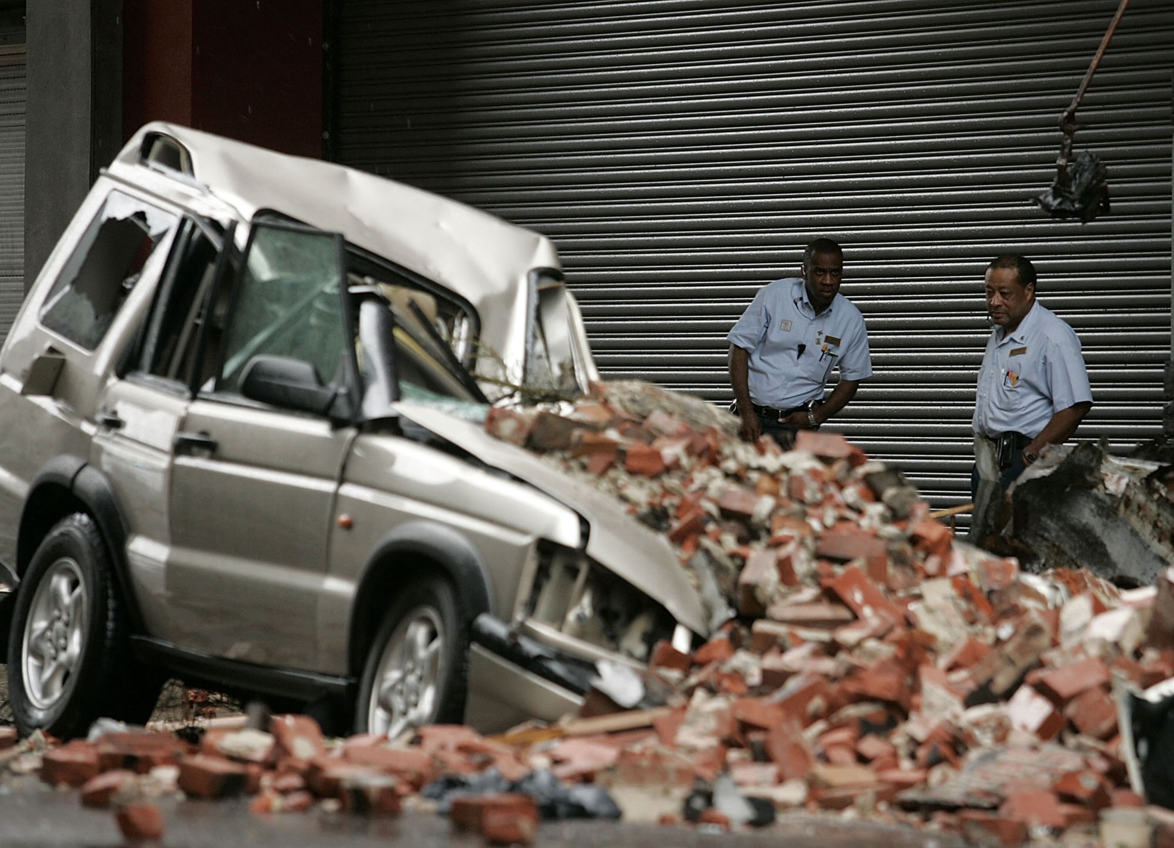 Two men look at a car that was damaged by bricks that fell due to Hurricane Katrina August 29, 2005 in New Orleans, Louisiana. Katrina was down graded to a category 4 storm as it approached New Orleans. (Photo by Mark Wilson/Getty Images)