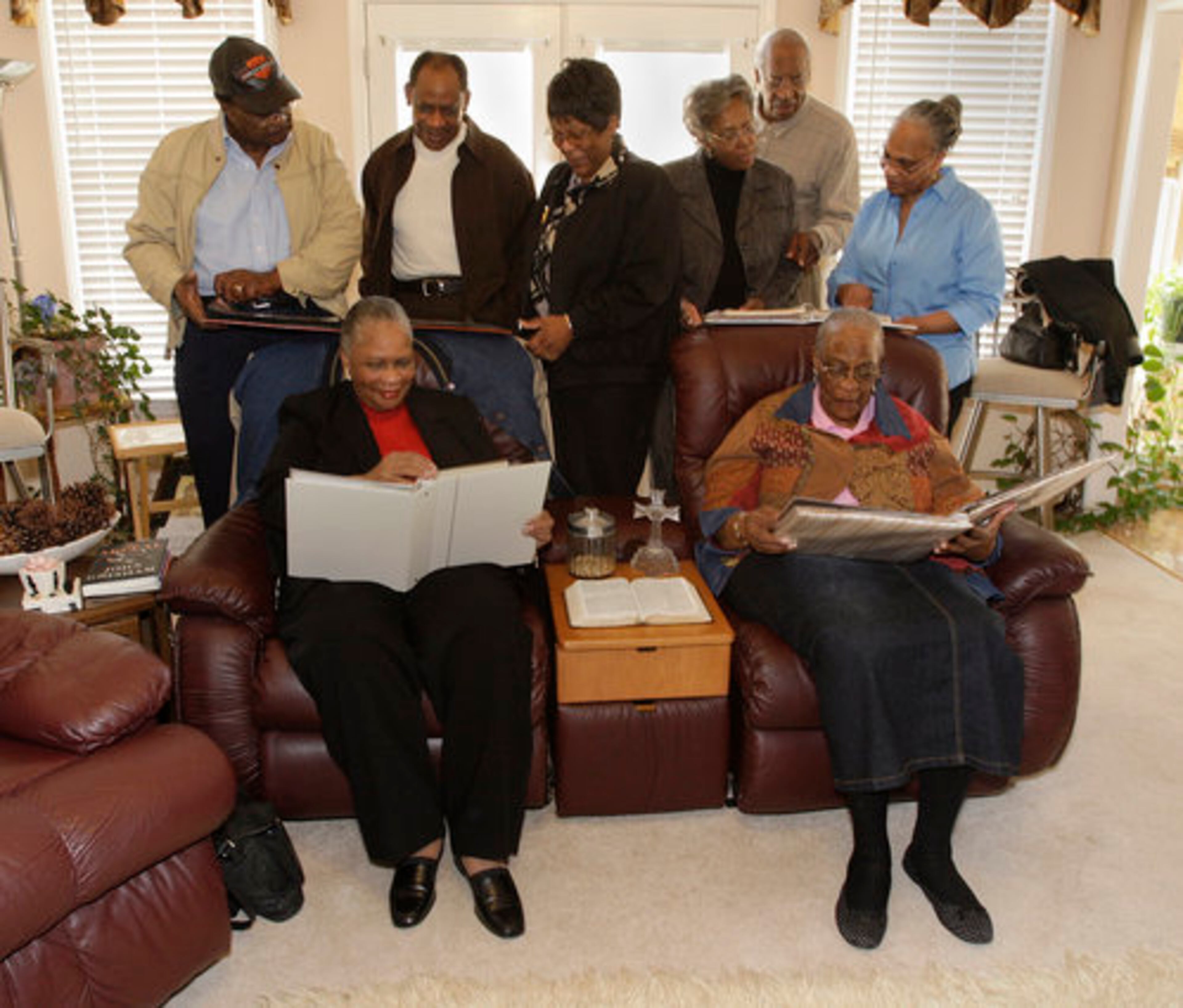 The siblings look over family photo albums. Seated (from left) are Laverne Baker and Barbara Lester. Standing (from left) are Jerome Woods, Roger Woods Jr., Brenda Drucilla Woods, sister-in-law Mary Woods, Kenneth Woods and Marcia Glenn Hunter,.