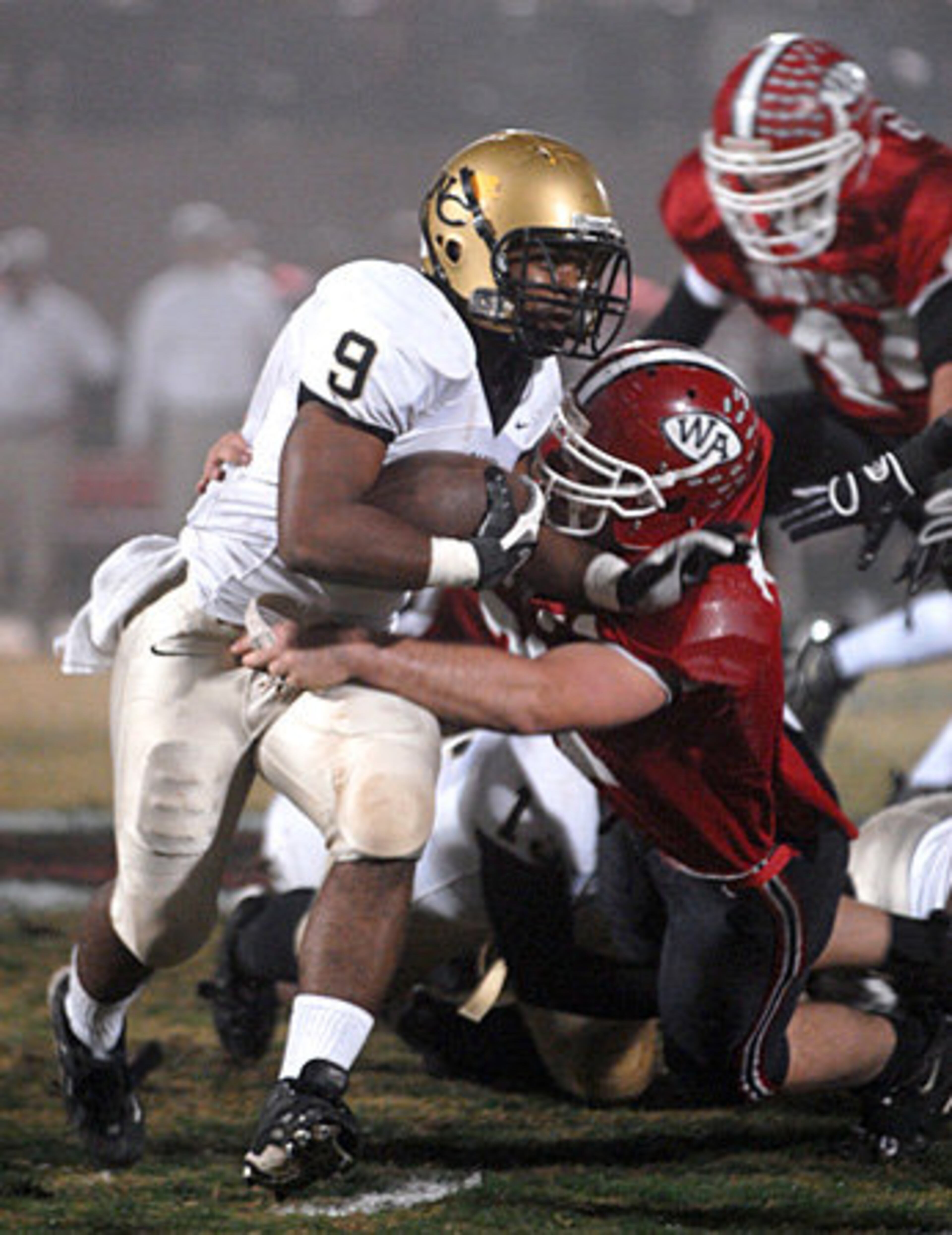 Washington County High's Keith Swint (No. 9) pushes for yardage against Woodward Academy on a foggy Friday night. Woodward's War Eagles hosted Washington County's Golden Hawks in the first round of the Class AAA playoffs.