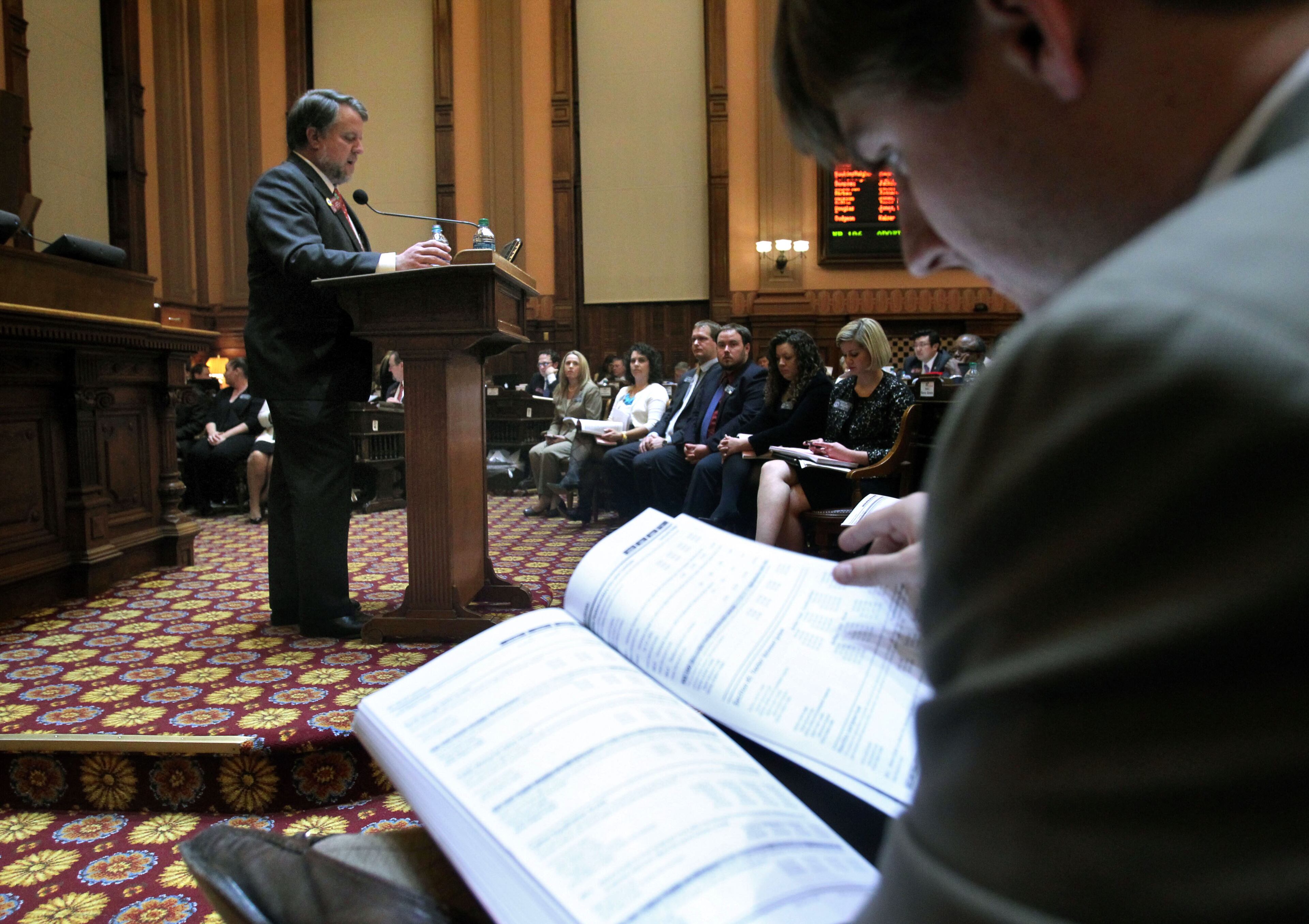 Buck Dixon of the House Budget and Research Office, right, looks over the proposed state budget as House Appropriations Chairman Terry England, R-Auburn, speaks to the rest of the House about it prior to passage.