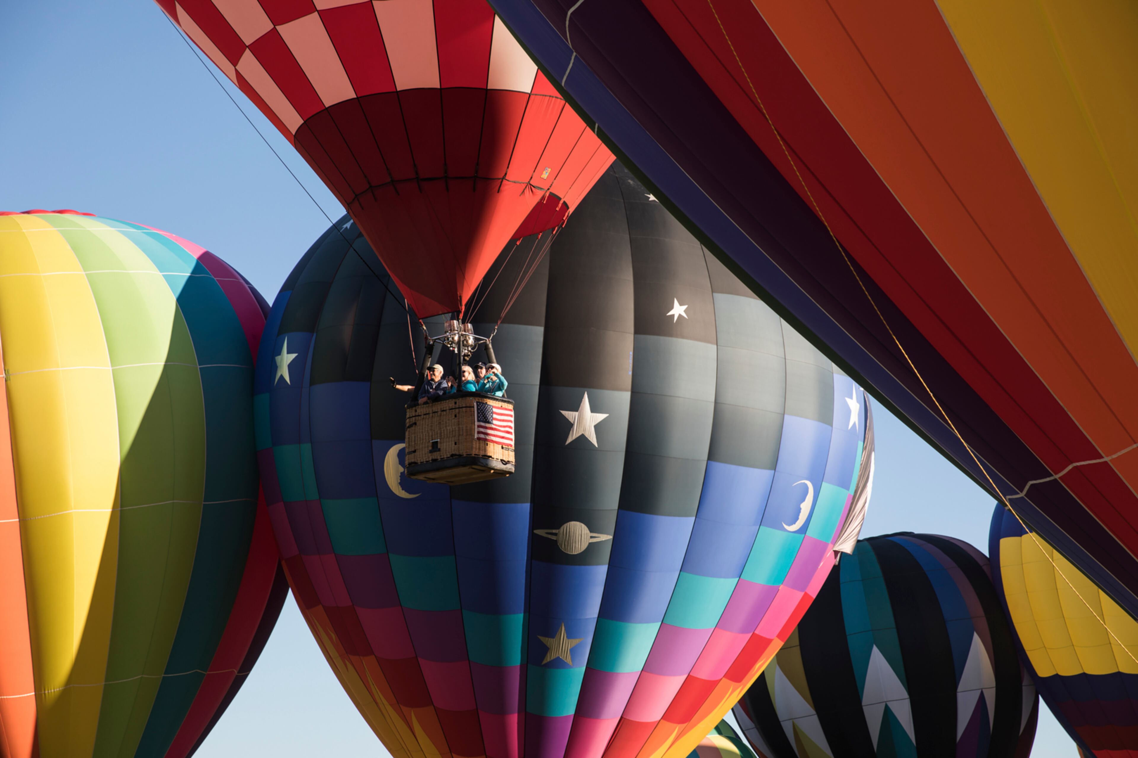 A basket of balloonists float amid a snug group of fellow sky-bound enthusiasts during the 35th Annual QuickChek New Jersey Festival of Ballooning over Solberg Airport in Whitehouse Station, N.J., July 30, 2017. (Jackie Molloy/The New York Times)