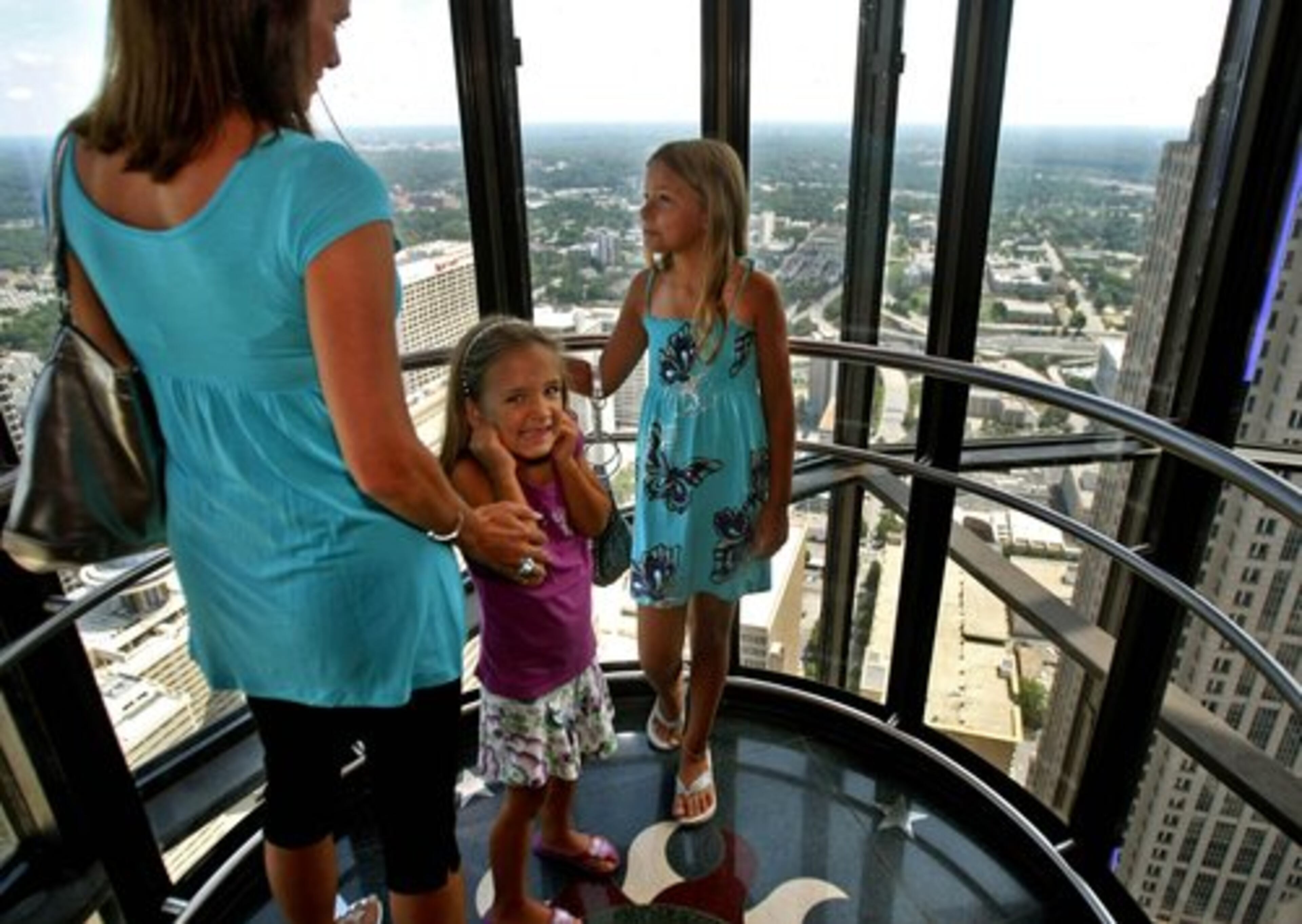 Allison Jones, 6, of Sandy Springs, center, holds her ears after the altitude change from the 5th floor to the 72nd floor as they rode to the Sun Dial in the hotel's scenic elevator.