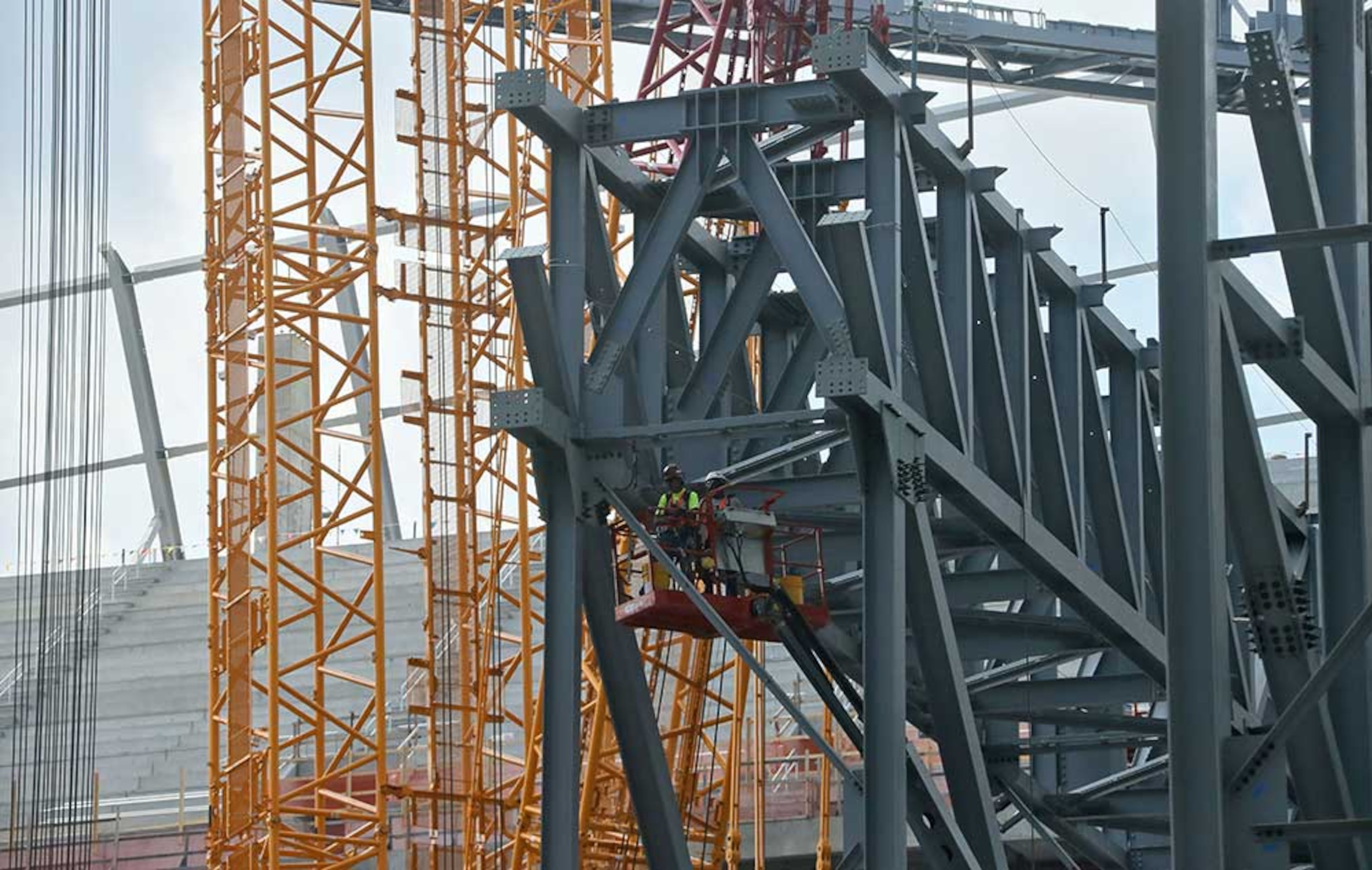 The field level is filled with steel work and cranes as tower construction and roof steel truss ground assembly continues inside the bowl.