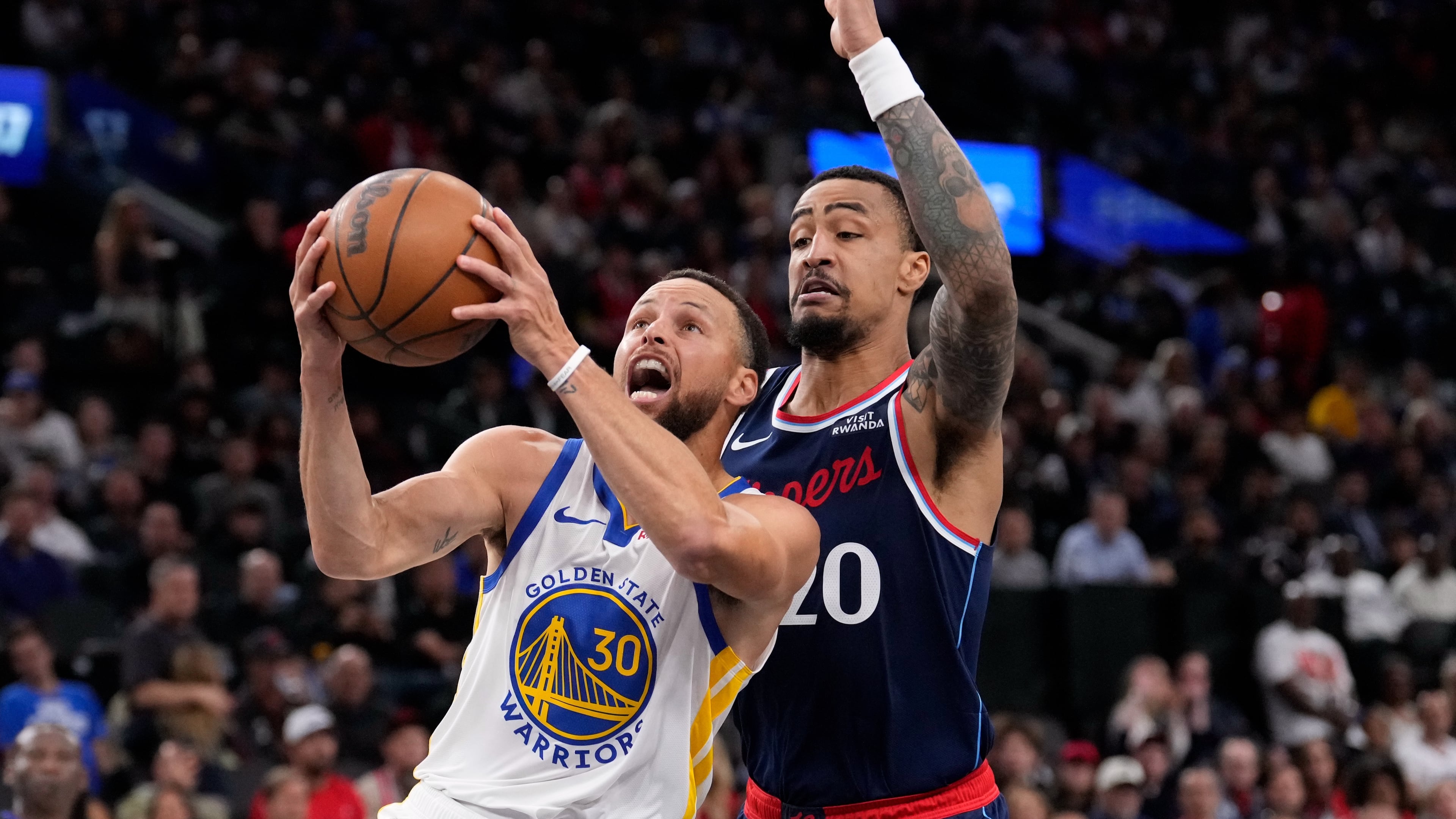 Golden State Warriors guard Stephen Curry, left, shoots as LA Clippers forward John Collins defends during the first half of an NBA play-in tournament basketball game Wednesday, April 15, 2026, in Inglewood, Calif. (AP Photo/Mark J. Terrill)