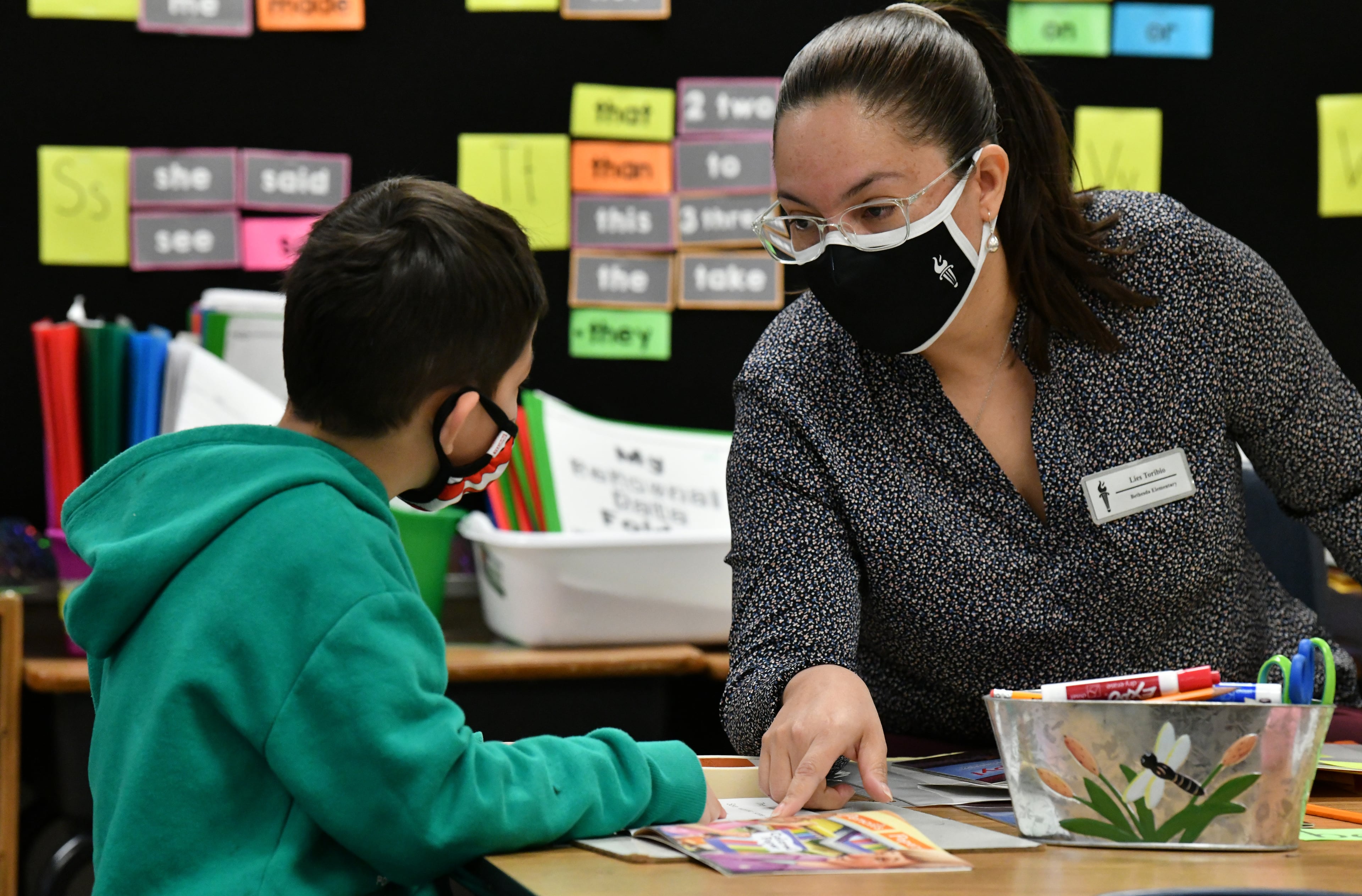Lies Toribio, a first-year teacher who was once a custodian, helps her student Jayden Mijango with reading as she teaches her kindergarten class at Bethesda Elementary in Lawrenceville on April 22, 2021. (Hyosub Shin / Hyosub.Shin@ajc.com)
