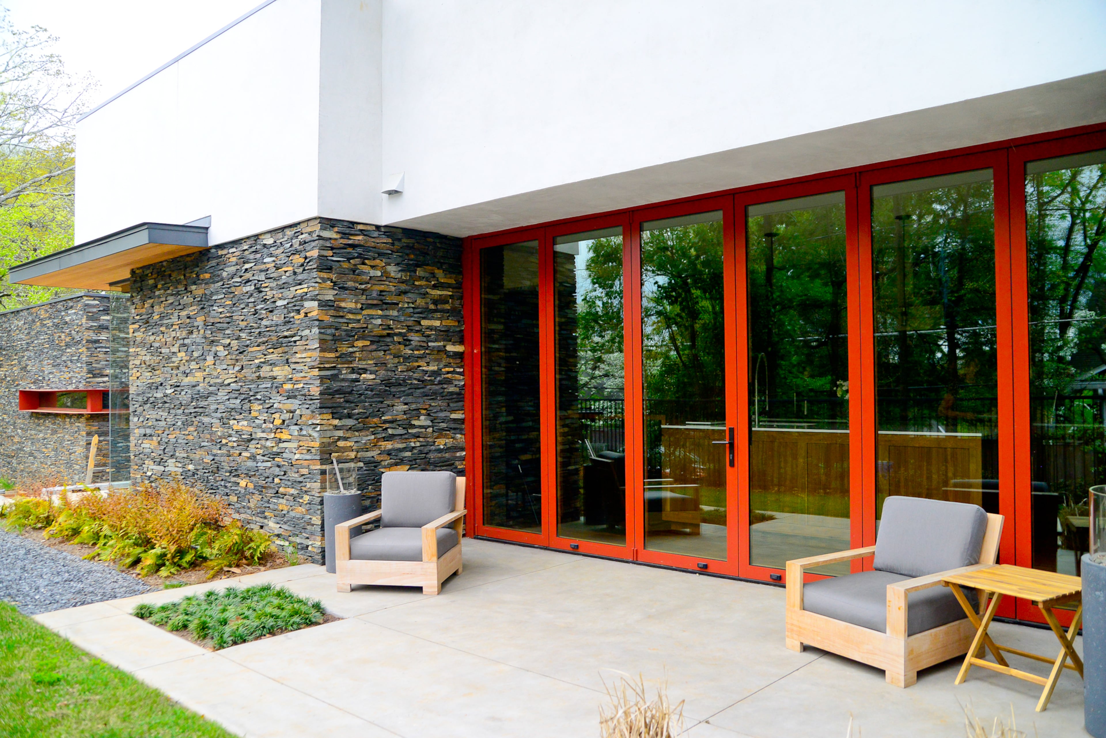 The homeowners worked with Core Landscape Group on the outdoor spaces, which includes a concrete patio off the kitchen with RH chairs.
